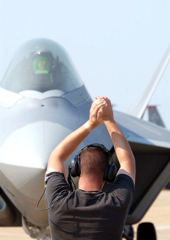 LANGLEY AIR FORCE BASE, Va. -- Senior Airman Rick Alexander marshals in Col. James Hecker after returning from a simulated F/A-22 Raptor combat sortie during an exercise here. The exercise evaluated the 1st Fighter Wing's ability to prepare and deploy people, equipment and support assets to a combat environment.  Colonel Hecker is the 27th Fighter Squadron commander. (U.S Air Force photo by Staff Sgt Eric T. Sheler)

