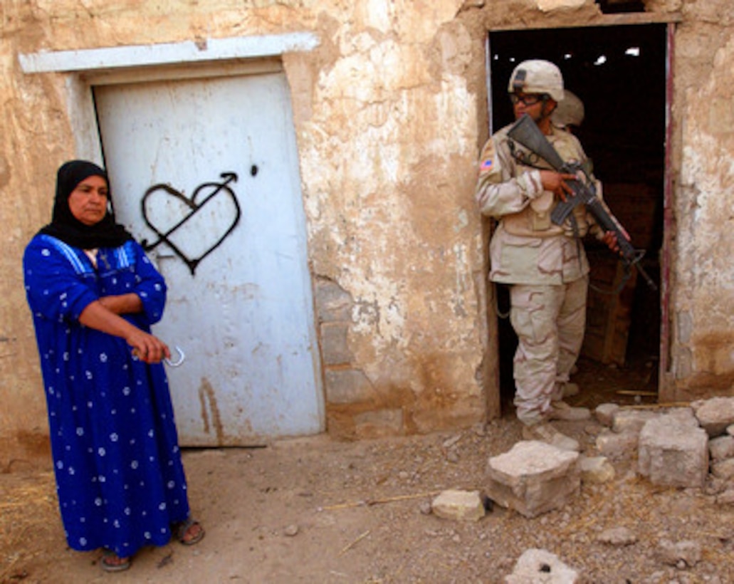 Army Spc. Johnny Rodriguez keeps his eye on an Iraqi woman as other members of his squad searches a shed on her farm in Samarra, Iraq, on July 27, 2005. Coalition forces raided the farm after an informant tipped off authorities to the location of a weapons dealer and possible weapons cache. Rodriguez is attached to the Army's 70th Engineer Battalion, 3rd Brigade, 1st Armored Division. 
