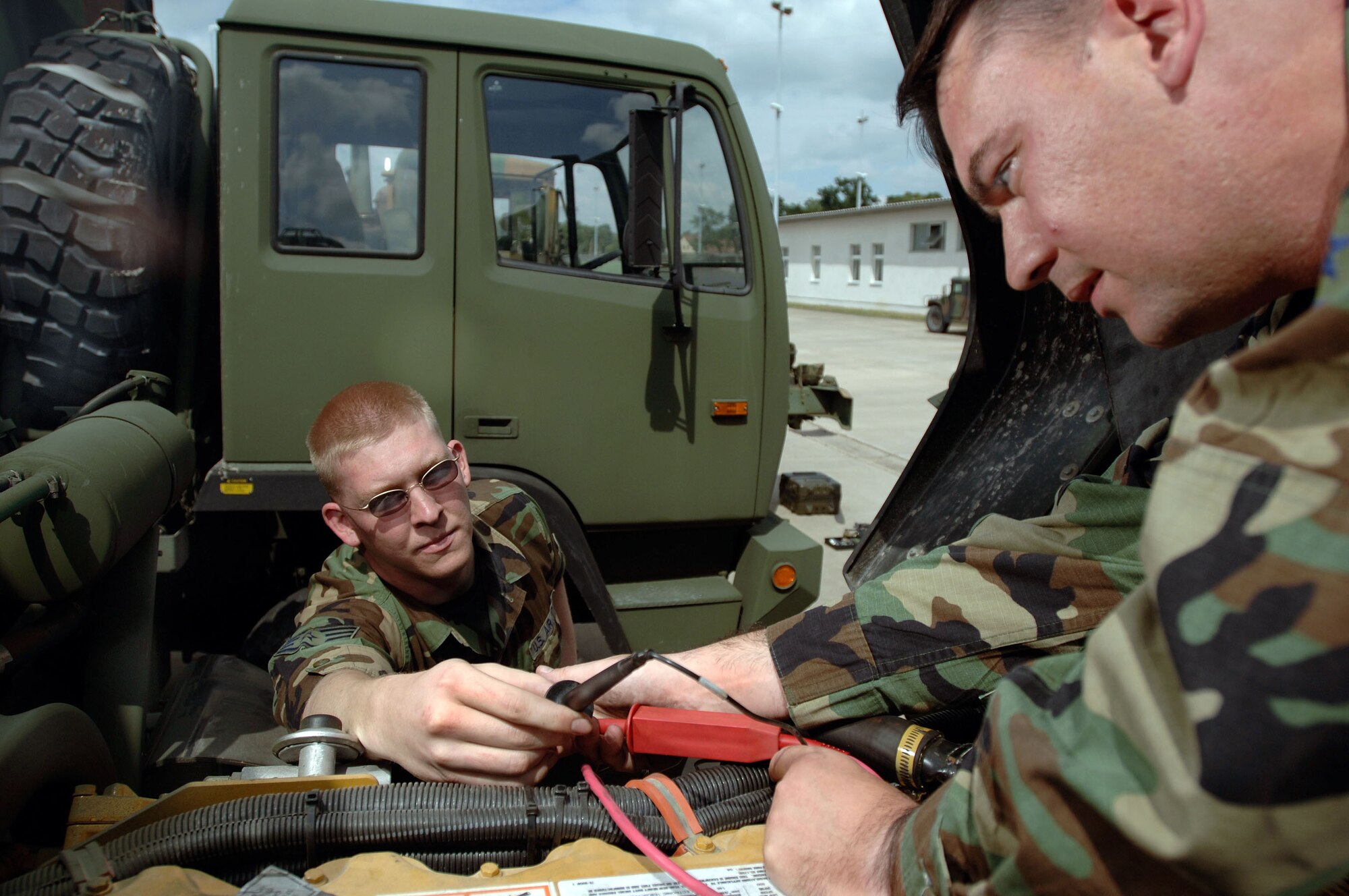 SULLIVAN BARRACKS, Germany -- Staff Sgt. Kyle Polencheck (left) helps Tech. Sgt. Jeffery Egbert with lead cables as they check a faulty sensor on the engine of a light military tactical vehicle.  The vehicle specialists help maintain a fleet of more than 85 vehicles ranging from Humvees to 5-ton military tactical trucks their squadron uses in Iraq and Afghanistan.  They are assigned to the 4th Air Support Operations Squadron here.  (U.S. Air Force photo by Senior Master Sgt. Keith Reed)