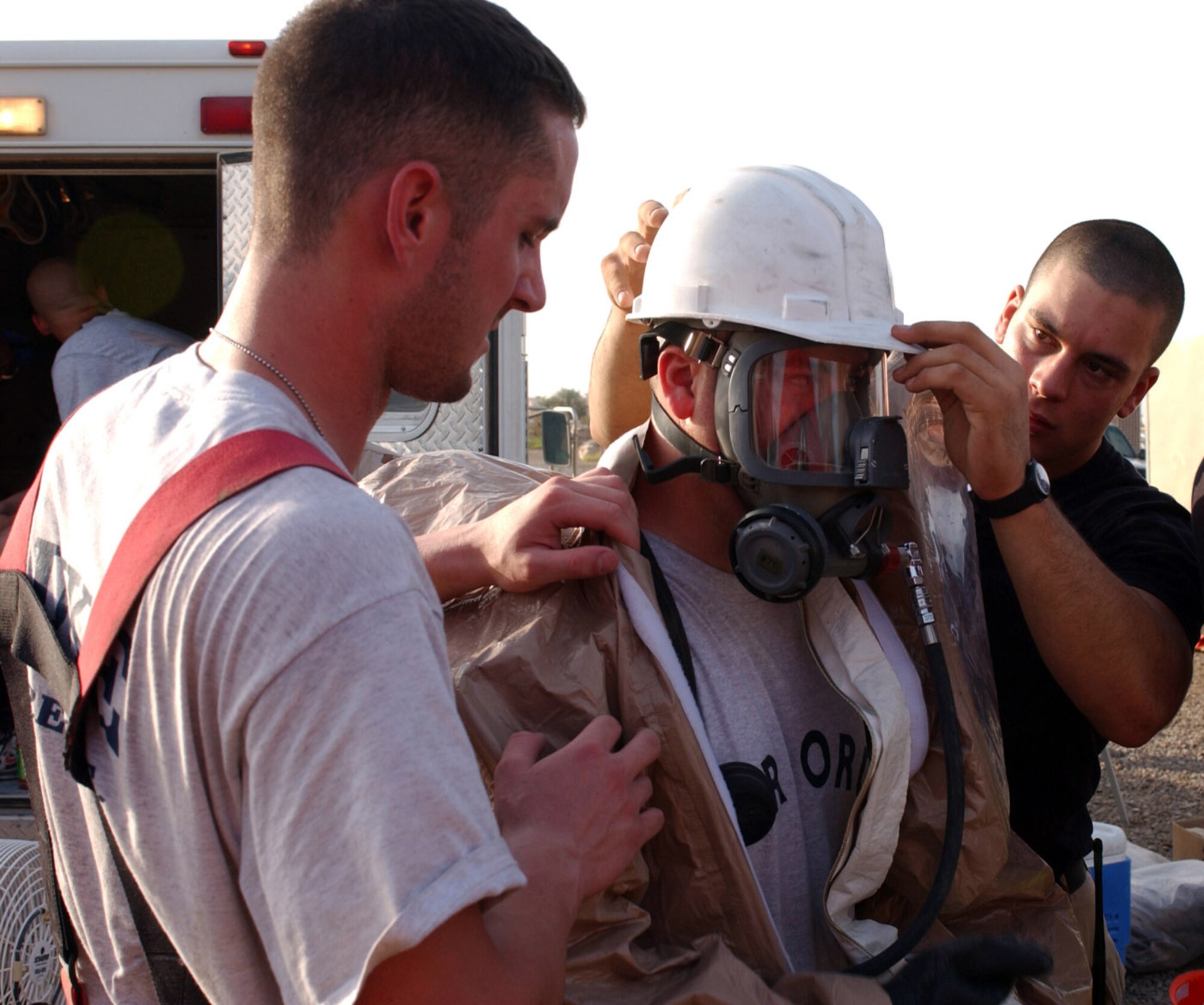 BAGHDAD, Iraq -- Airmen 1st Class Richard Ellis (left) and Matthew Metzger help Airman 1st Class Mitchel Kukykendal suit up in preparation to enter an exercise evaluation area here. The Airmen are hazardous material response team members with the 447th Expeditionary Civil Engineer Squadron. Airman Ellis is deployed from Luke Air Force Base, Ariz., Airman Metzger is deployed from Kadena Air Base, Japan, and Airman Kukykendal is deployed from Lajes Field, Azores. (U.S. Air Force photo by Tech. Sgt. Brian Davidson)
