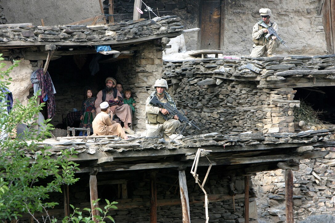 (Left) Lance Cpl. Ryan R. Irving, infantryman, from Elburn, Ill. and Lance Cpl. Curtis D. Land, infantryman, from Cedar Falls, Iowa take security posts during a meeting between Marines and villagers. In preparation for elections next month, Marines conducted a preemptive attack on known areas of anti-coalition militia activity.
