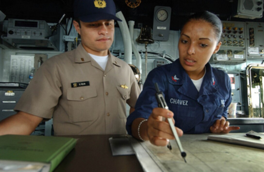 U.S. Navy Petty Officer 2nd Class Aurora Chavez (right) explains the plotting of the position of the USS Thomas S. Gates (CG 51) to Peruvian Navy Lt. j.g. Gustavo Mejia while underway in the Pacific Ocean for Exercise Panamax '05 on Aug. 11, 2005. Fifteen nations are participating in the exercise, which is designed to develop responses to threats against the Panama Canal. Chavez is a Navy quartermaster. Mejia is visiting the Gates from the Peruvian ship BAP Villavisencio (FM 52). 