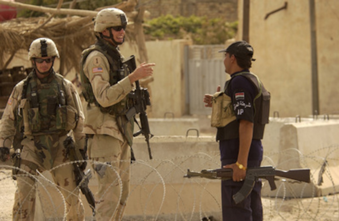 U.S. Army 1st Lt. James Meeks (center) and Staff Sgt. Richard Gentry (left) talk with an Iraqi police officer about force protection around the voter registration site in Al Abara, Iraq, on Aug. 12, 2005. 