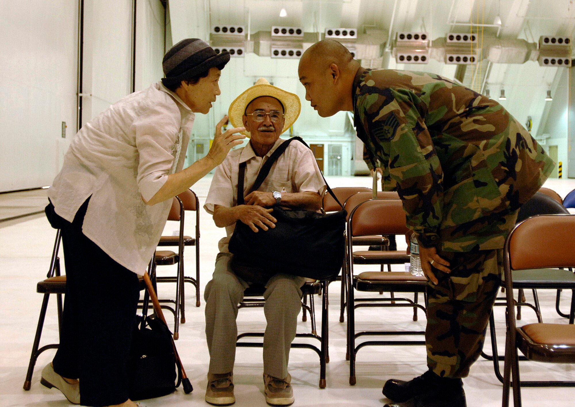 ANDERSEN AIR FORCE BASE, Guam -- Staff Sgt. Bernard Mallada speaks with an elderly Japanese tourist after their plane was diverted here Aug. 19.  More than 800 passengers arrived safely and cleared through customs after their commercial flights were diverted because of an emergency that temporarily closed Won Pat International Airport, Guam.  Airmen and local custom agents and authorities worked together to process passengers on eight airliners.  Sergeant Mallada is assigned to the 36th Maintenance Squadron.  (U.S. Air Force photo by Staff Sgt. Bennie J. Davis III)