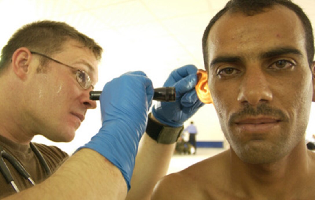 U.S. Army Capt. Jeremy Orr (left) examines an Iraqi police recruit during a screening process at the Police Training Facility in Najaf, Iraq, on Aug. 17, 2005. Orr and his fellow soldiers from the 198th Armor, 155th Brigade Combat Team are examining the candidates to ensure that they can read and write and that they are physically able to perform the job. 