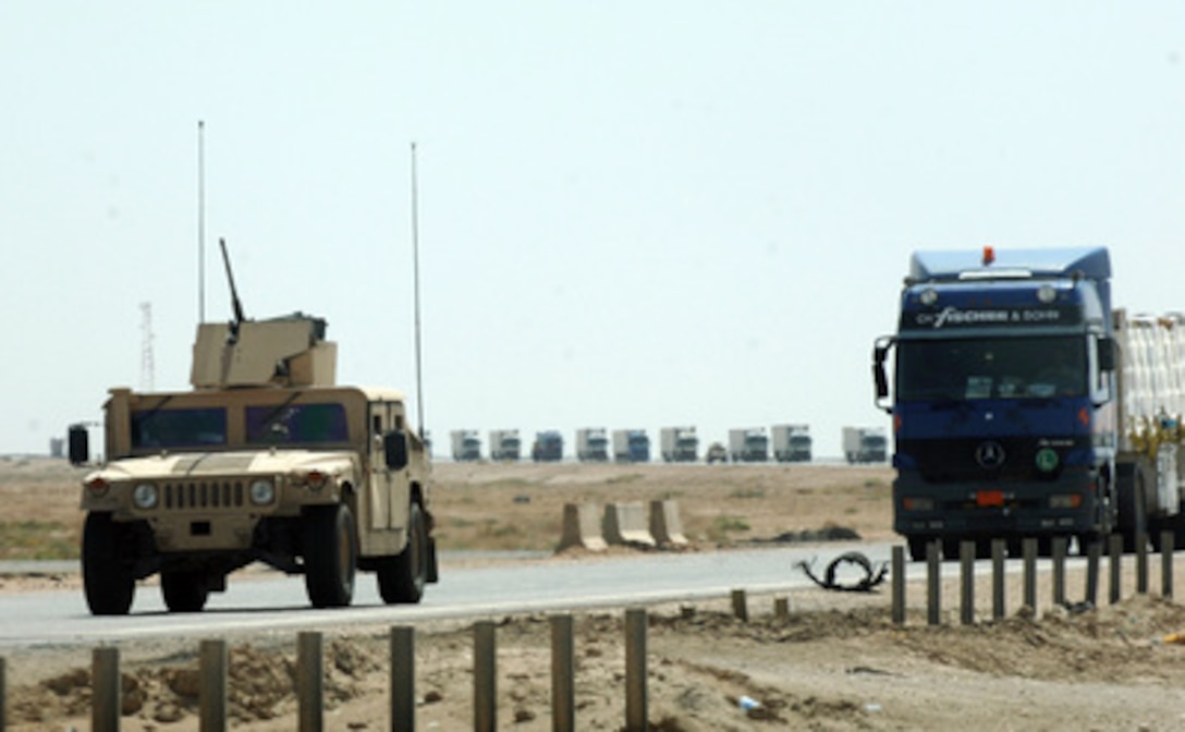 A U.S. Army Humvee escorts a long line of tractor-trailers as they cross the desert in Iraq on Aug. 10, 2005. The truck convoys bring thousands of tons of supplies to U.S. and coalition forces in Iraq. 