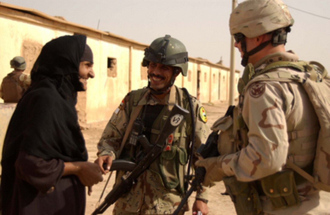 Iraqi Army Sgt. 1st Class Tho-Falgar (center) and U.S. Army Staff Sgt. Steven Rinaldi (right) talk with an elderly woman during a patrol of Al Hizam Village in the Diyala Province of Iraq, on July 12, 2005. Tho-Falgar is attached to the Iraqi Army's 3rd Battalion, 1st Brigade, 5th Division. Rinaldi is the non-commissioned officer in charge of the Military Transition Team. 