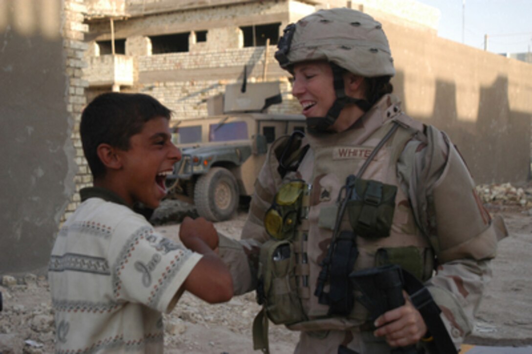 Army Sgt. Stephanie White plays a hand game with 13-year-old boy during a visit to the al-Zohour Patrol in Baghdad, Iraq, on Aug. 20, 2005. White is attached to the Army's 64th Military Police Company, 720th MP Battalion from Fort Hood, Texas. 