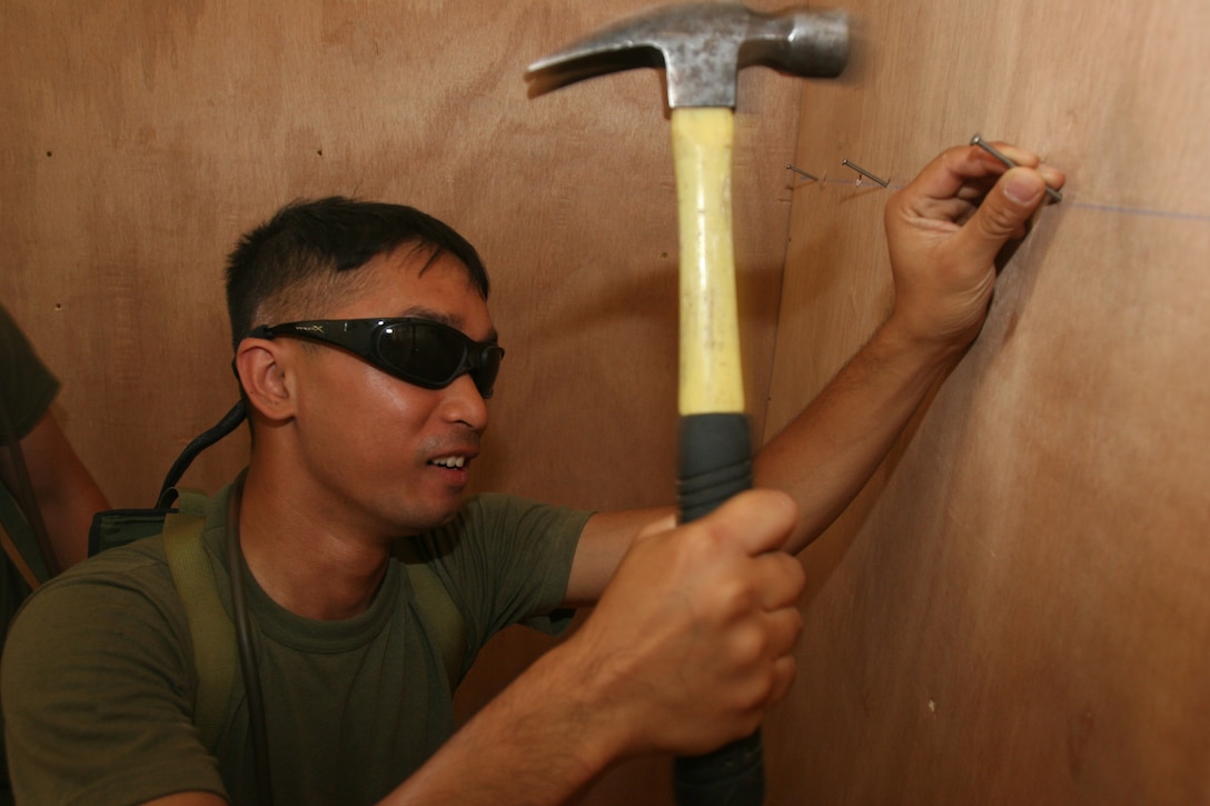 AL ASAD, Iraq ? Sergeant Chantra Chhom, a seat mechanic with Marine Attack Squadron 223, and Jacksonville, Fla., native, hammers a nail into the wall to support their helmets. A few Bulldogs arrived here two weeks ago to prepare work spaces.