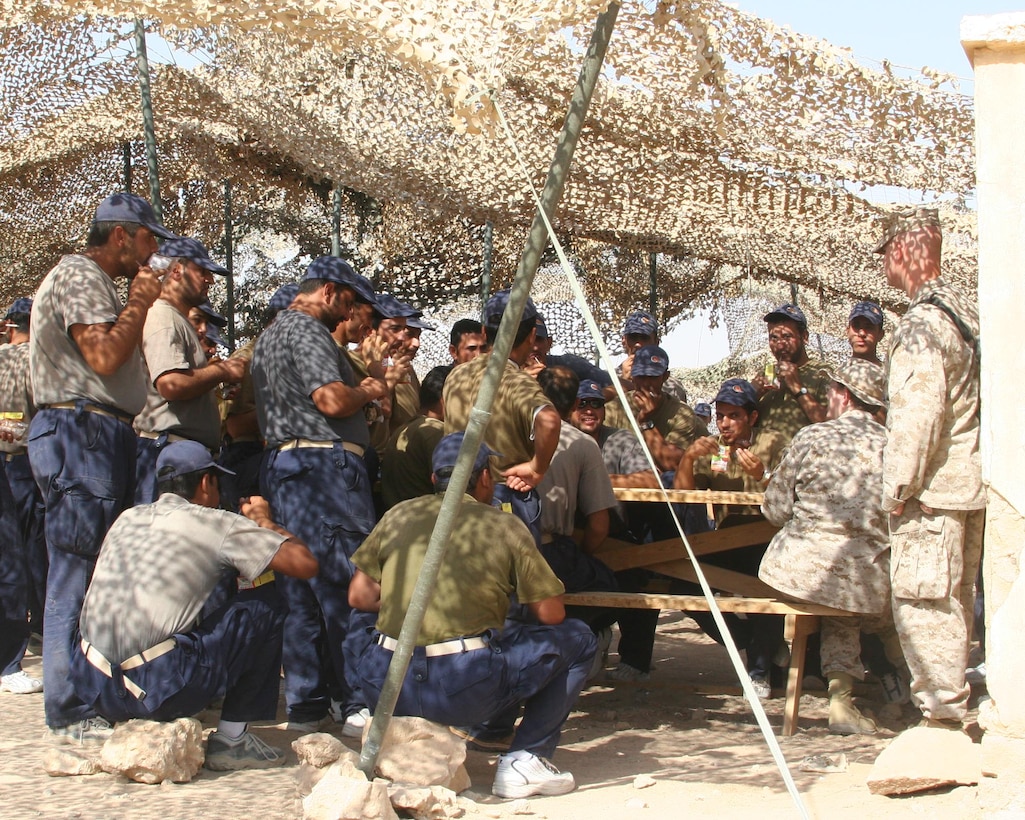 AL ASAD, Iraq - A group of Iraqi policemen congregate under camouflaged netting for refreshments following their graduation Aug. 24 from an advanced police officer training course here.  More than 100 Iraqi men graduated from the advanced course and will head back to their stations in Iraq better prepared to face the challenges which lie ahead as they seek to secure a brighter future for their country.