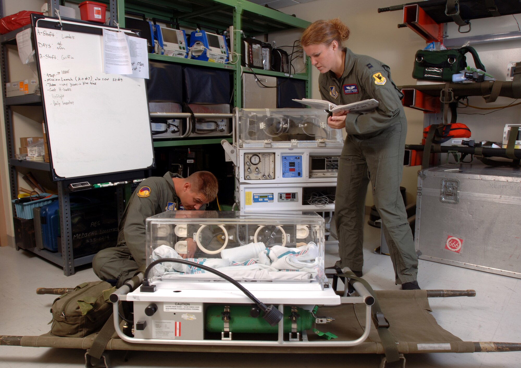 KADENA AIR BASE, Japan -- Staff Sgt. Joe Lueders (left) and Capt. Jennifer Prosser prepare their equipment before a mission here.  The mission of the 18th Aeromedical Evacuation Squadron is to provide a flexible, seamless and responsive system capable of prompt and appropriate patient movement.  Sergeant Lueders is a technician, and Captain Prosser is a flight nurse.  (U.S. Air Force photo by Master Sgt. Val Gempis)