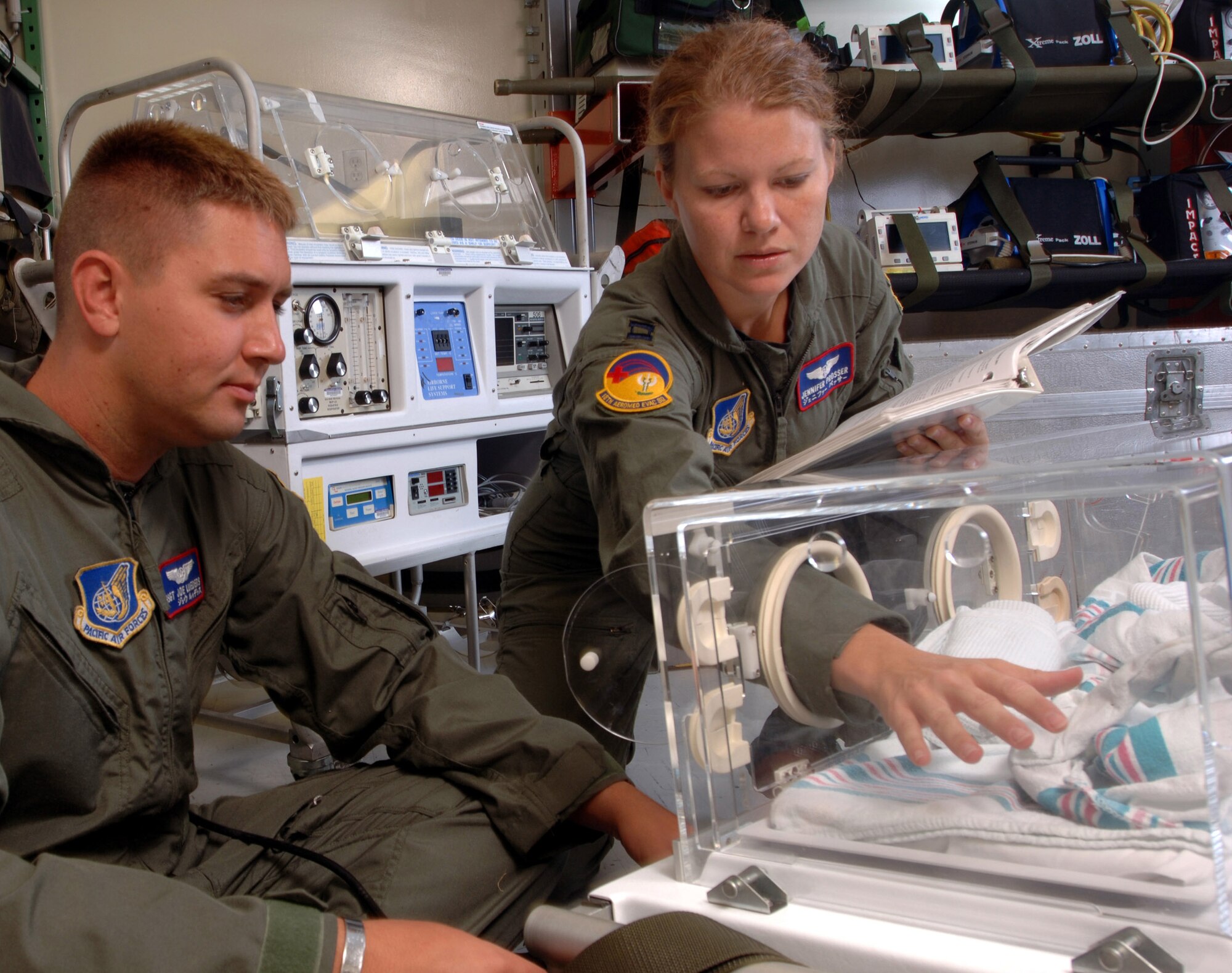 KADENA AIR BASE, Japan -- Capt. Jennifer Prosser (right) checks the temperature inside a neonatal transportation system here, while Staff Sgt. Joe Lueders observes.  The mission of the 18th Aeromedical Evacuation Squadron is to provide a flexible, seamless and responsive system capable of prompt and appropriate patient movement.  Sergeant Lueders is a technician, and Captain Prosser is a flight nurse.  (U.S. Air Force photo by Master Sgt. Val Gempis)