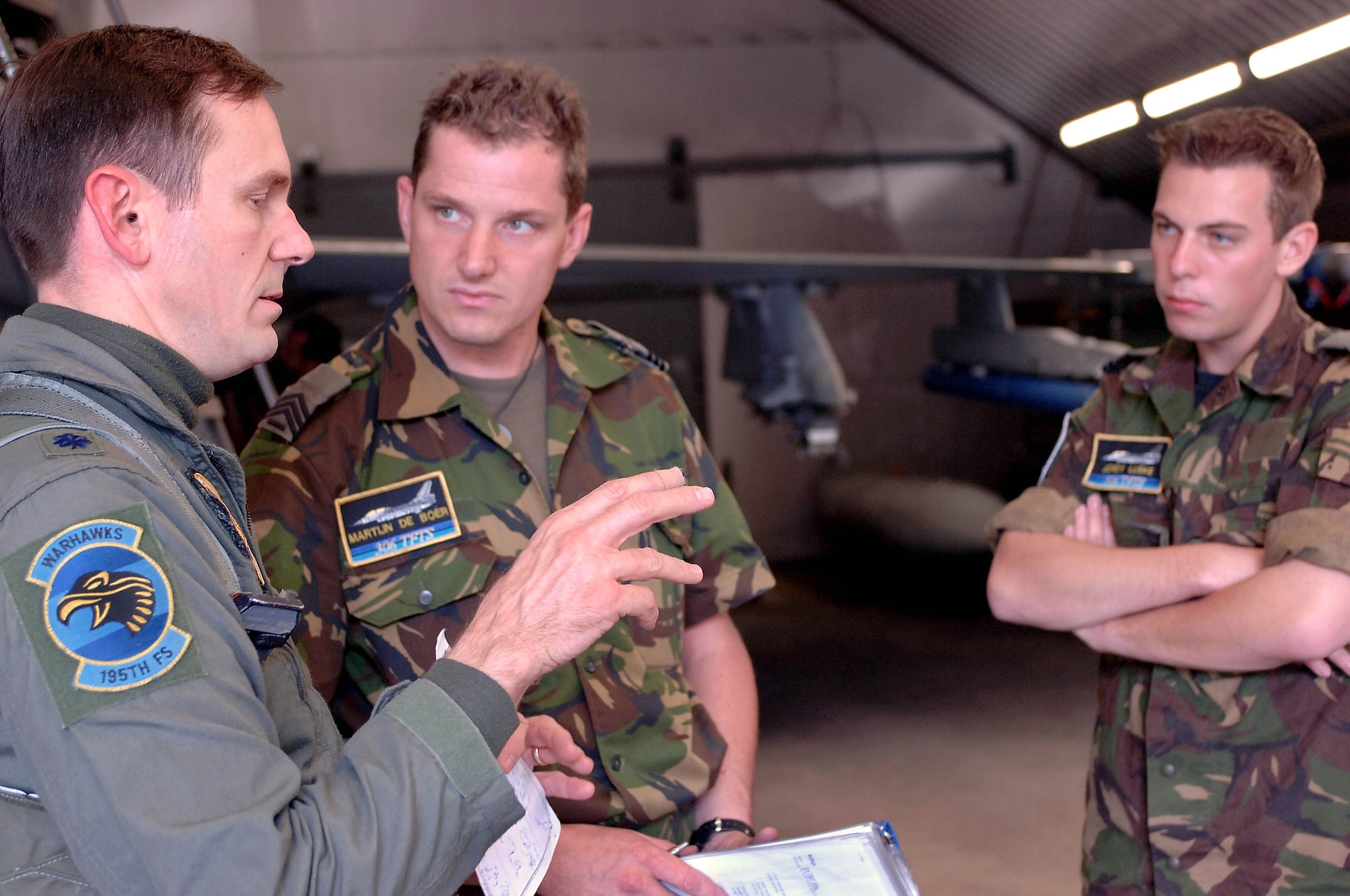 VOLKEL AIR BASE, Netherlands -- Lt. Col. David Stein talks about a sortie with Dutch air force crew chiefs Sgt. Martijn De Boer and Cpl. Jordy Luske.  The colonel is an exchange pilot from the Arizona Air National Guard's 162nd Fighter Wing at Tucson, Ariz.  After a three-year tour with the Dutch air force's 1st Fighter Wing, he will soon return home and pass on what he has learned about the Netherlands's NATO role to his fellow pilots.  (U.S. Air Force photo by Senior Master Sgt. Keith Reed)