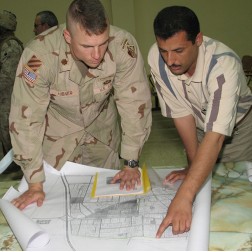 U.S. Army Maj. Dan Hibner and Fallujah Water Department Director Hamed Munster go over the drawings of a proposed new water main in Fallujah, Iraq, on Aug. 22, 2005. Hibner is the officer in charge of the U.S. Army Corps of Engineers Gulf Region Central District Fallujah Office. 