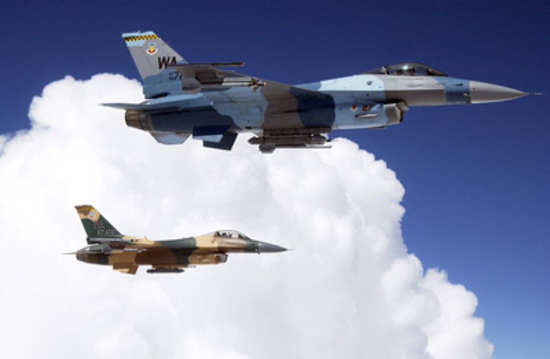 Two F-16 Fighting Falcons from the 64th Aggressor Squadron, Nellis Air Force Base, Nev., wait to be refueled by a KC-135 Stratotanker during a Red Flag mission over the Nevada Test and Training Range on Aug. 15, 2005. Red Flag is a quarterly, multi-national exercise designed to replicate the first ten days of war, giving pilots real world experience to increase their ability to survive in combat. The 64th Aggressor Squadron's F-16s have a unique paint scheme to match their role as simulated enemy MiG aircraft for the exercises. 