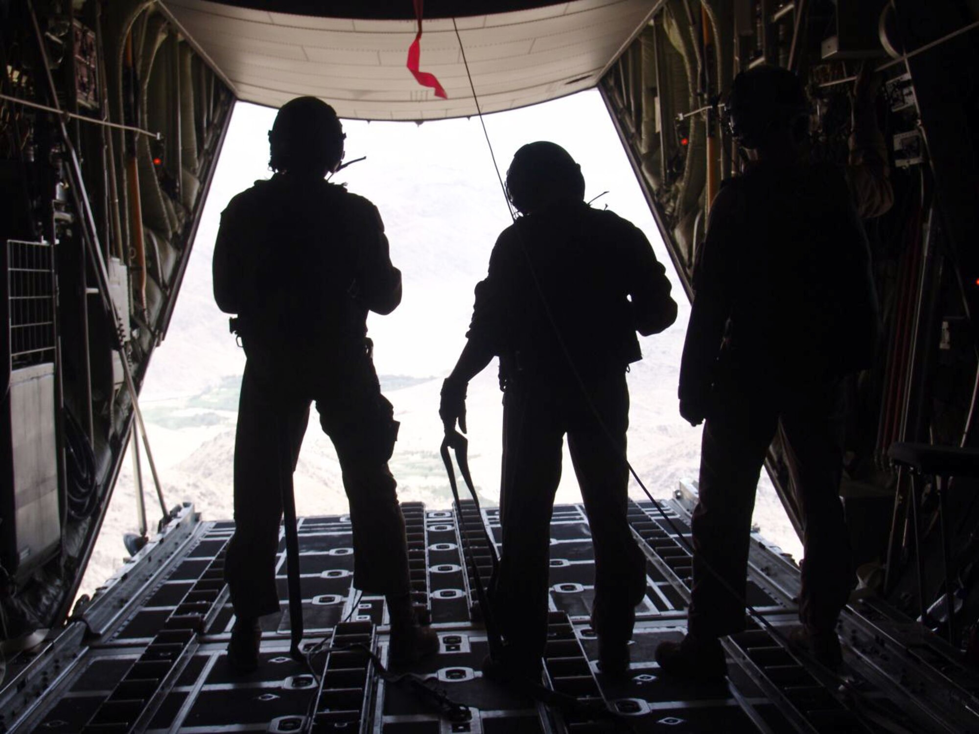 SOUTHWEST ASIA -- (From left) Tech. Sgt. Jermaine Parker and Staff Sgts. Chad Wells and Kelly Van Gundy gaze upon the Afghan terrain after airdropping two bundles containing more than 8,600 pounds of food, water and supplies.  The Airmen are C-130 Hercules loadmasters with the 738th Expeditionary Airlift Squadron at a forward-deployed location.  Sergeants Parker and Wells are deployed from the North Carolina Air National Guard's 156th Airlift Squadron, and Sergeant Van Gundy is deployed from Little Rock Air Force Base, Ark.  (U.S. Air Force photo by Staff Sgt. Carlos Diaz)