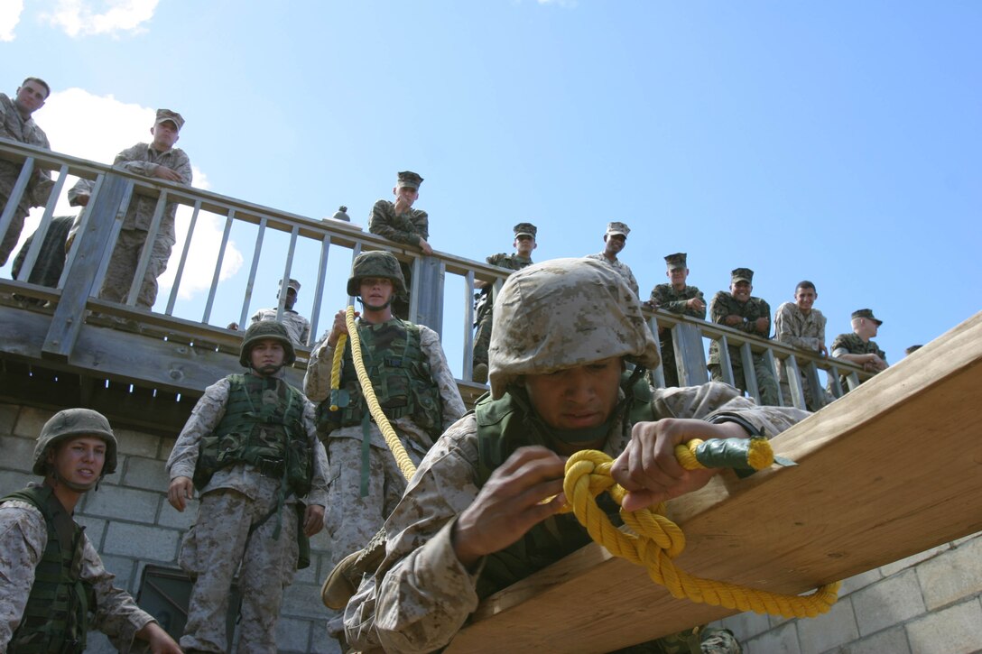 Cpl. Arthur Lopez, motor transport operator, Alpha Battery, 1st Battalion, 12th Marine Regiment, ties a knot around a board as his fellow Marines and team members look on in the hopes that this method will work and they will compete the mission before the time runs out. Each obstacle required the Marines, all their gear, and the tools they were provided to cross the obstacle and make it to the other side.