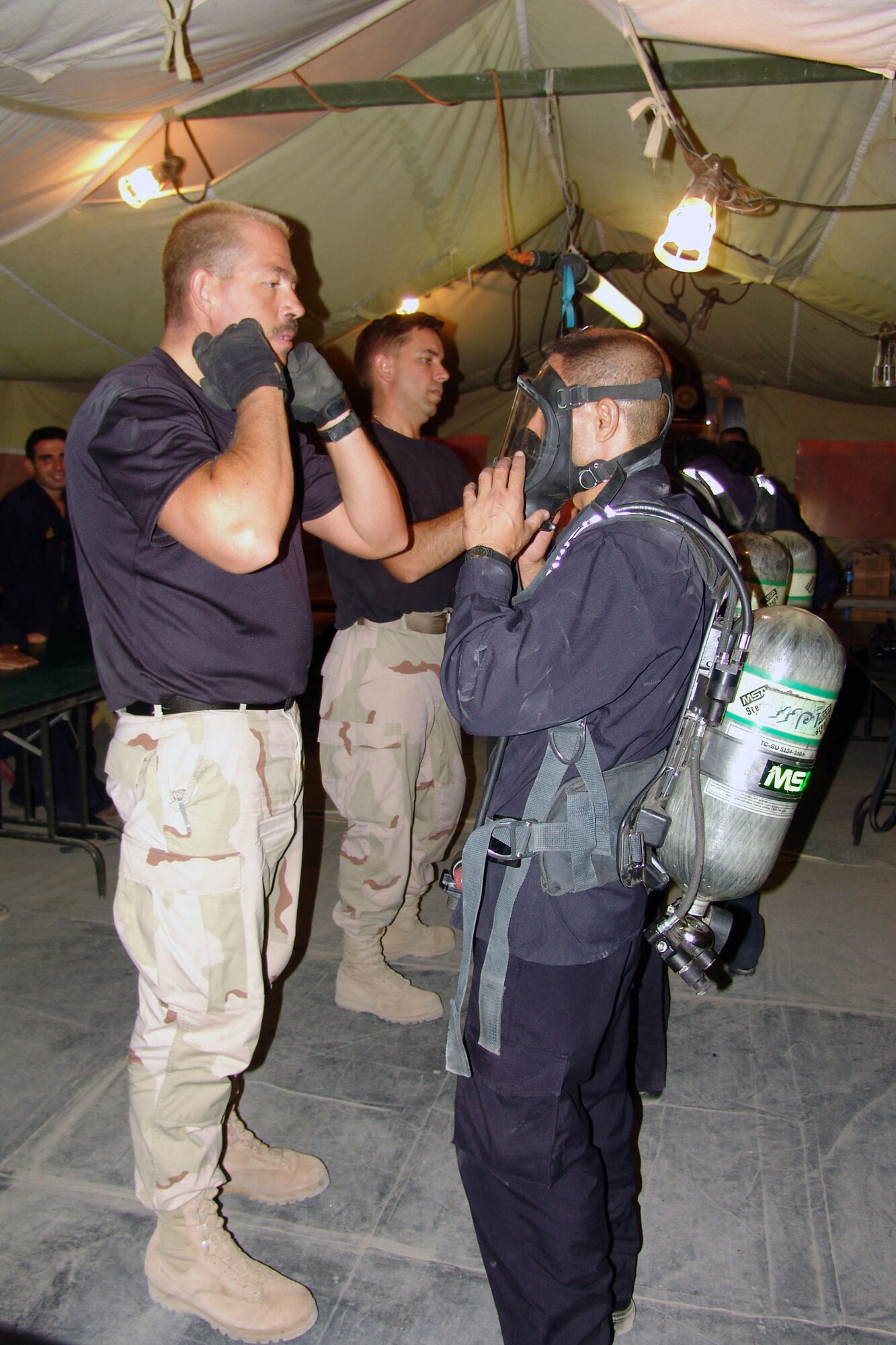 KIRKUK AIR BASE, Iraq -- Tech. Sgt. Norman Harrington shows an Iraqi firefighter how to remove his mask during.  Firefighters with the 506th Expeditionary Civil Engineer Squadron train oil pipeline protection personnel in first aid, cardio pulmonary resuscitation and basic firefighting skills.  (U.S. Air Force photo by Tech. Sgt. J. LaVoie) 