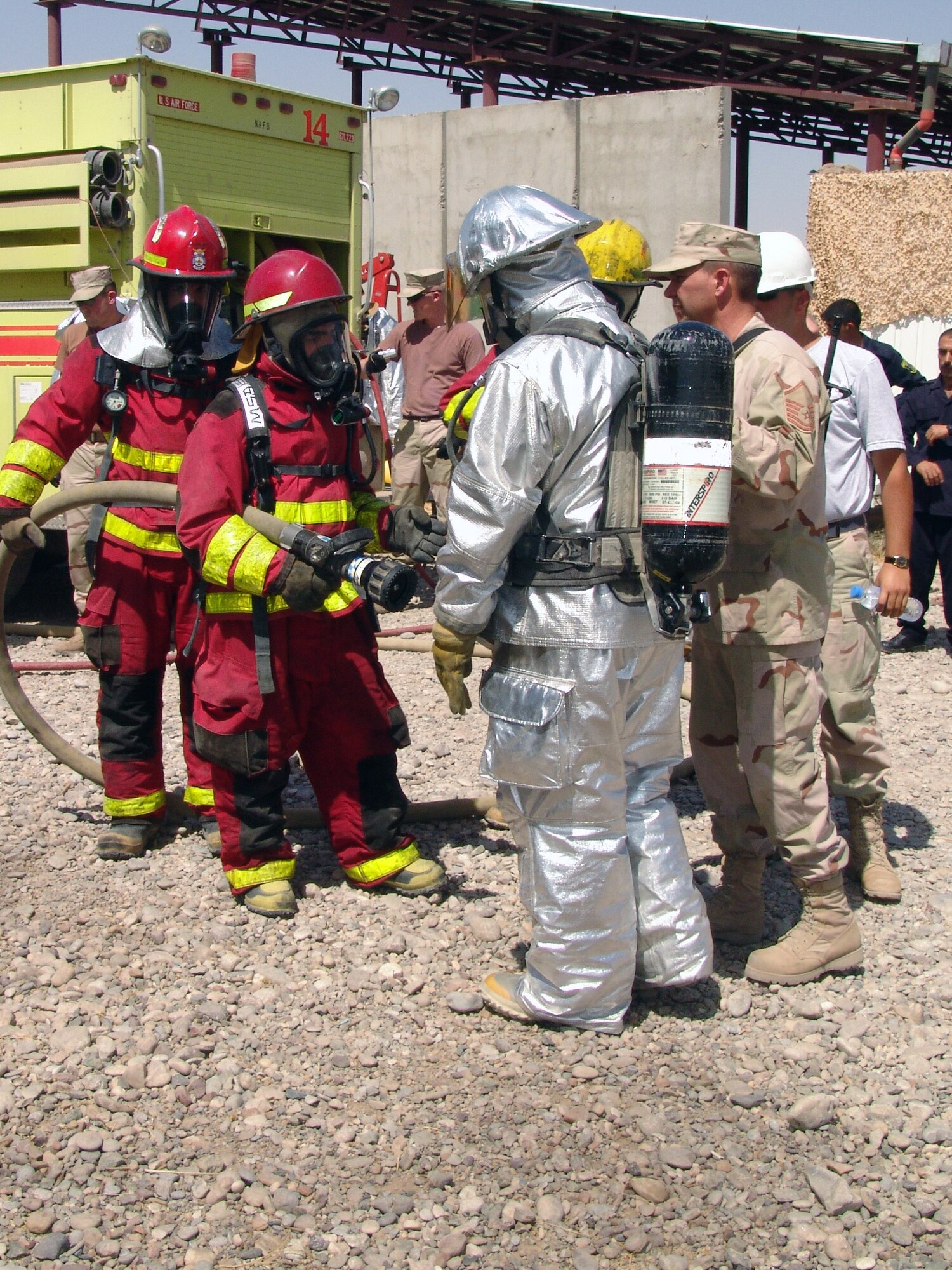 KIRKUK AIR BASE, Iraq -- American and Iraqi firefighters discuss procedures before entering an exercise area here.  Firefighters with the 506th Expeditionary Civil Engineer Squadron train oil pipeline protection personnel in first aid, cardio pulmonary resuscitation and basic firefighting skills.  (U.S. Air Force photo by Tech. Sgt. J. LaVoie) 