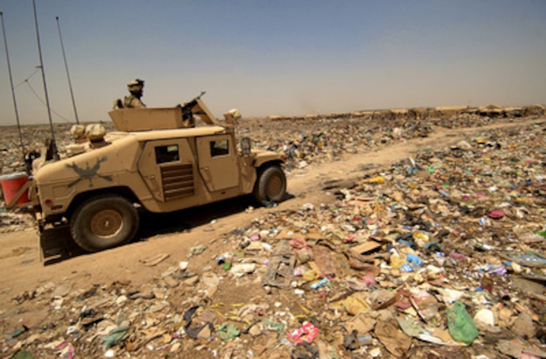 Soldiers from the Army's 3rd Brigade Reconnaissance Team, 3rd Infantry Division drive their Humvee on a path through the trash surrounding a village on the outskirts of Baghdad, Iraq, on Aug. 11, 2005. The soldiers will talk with the residents of the village to make sure no insurgents have sought refuge, while also handing out school supplies, toys and candy to the children. 