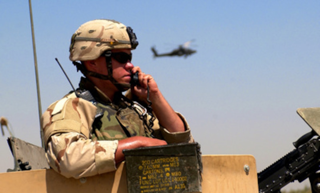 U.S. Army Spc. Aaron Lawrence uses the turret of a Humvee as a vantage point while trying to pinpoint the location of the triggermen involved in an improvised explosive device hit on a Humvee on Aug. 22, 2005, in Tarmiya, Iraq. Lawrence is attached to the 1st Battalion, 13th Armor Regiment, 3rd Brigade, 1st Armored Division. 