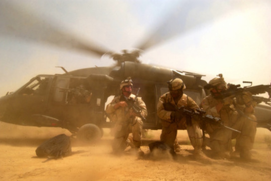 The rotor wash of a UH-60 Black Hawk helicopter kicks up clouds of dust as U.S. Army soldiers scan the perimeter of a landing zone for possible hostile forces near Baghdad, Iraq, on Aug. 26, 2005. The soldiers are with the 1st Battalion, 41st Infantry Regiment, 3rd Brigade, 1st Armored Division. 