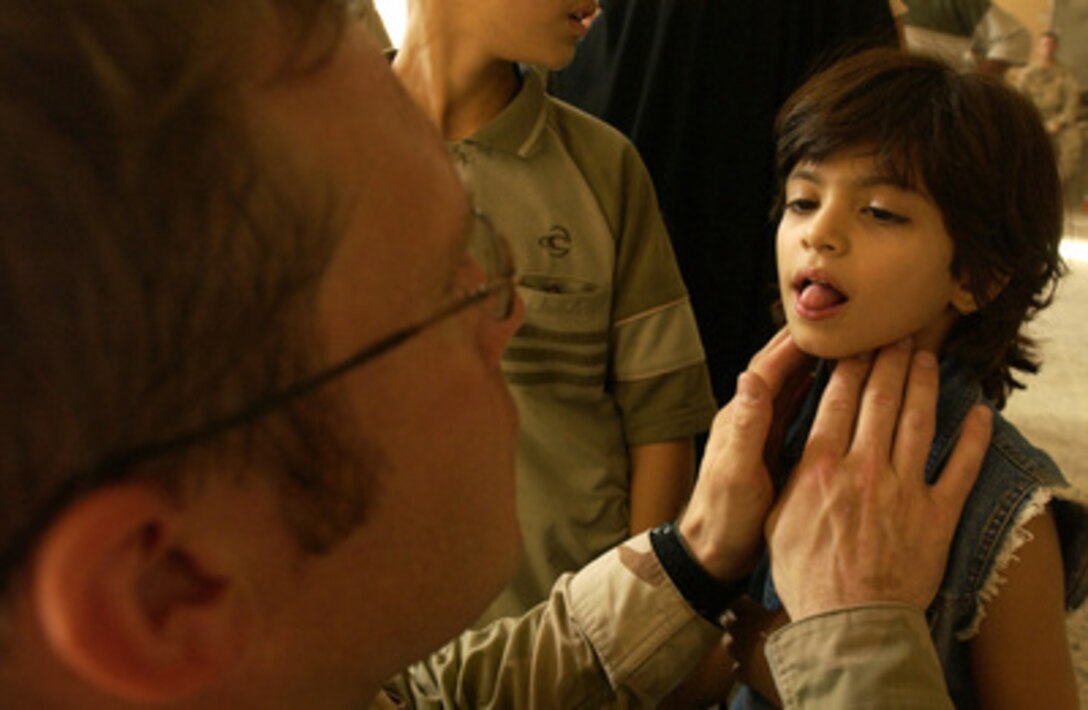 Army Capt. Jeremy Orr (left) examines the throat of an Iraqi girl during a Medical Civil Action Program visit in the city of Najaf, Iraq, on Aug. 28, 2005. Orr is deployed with the 198th Armor, 155th Brigade Combat Team. 