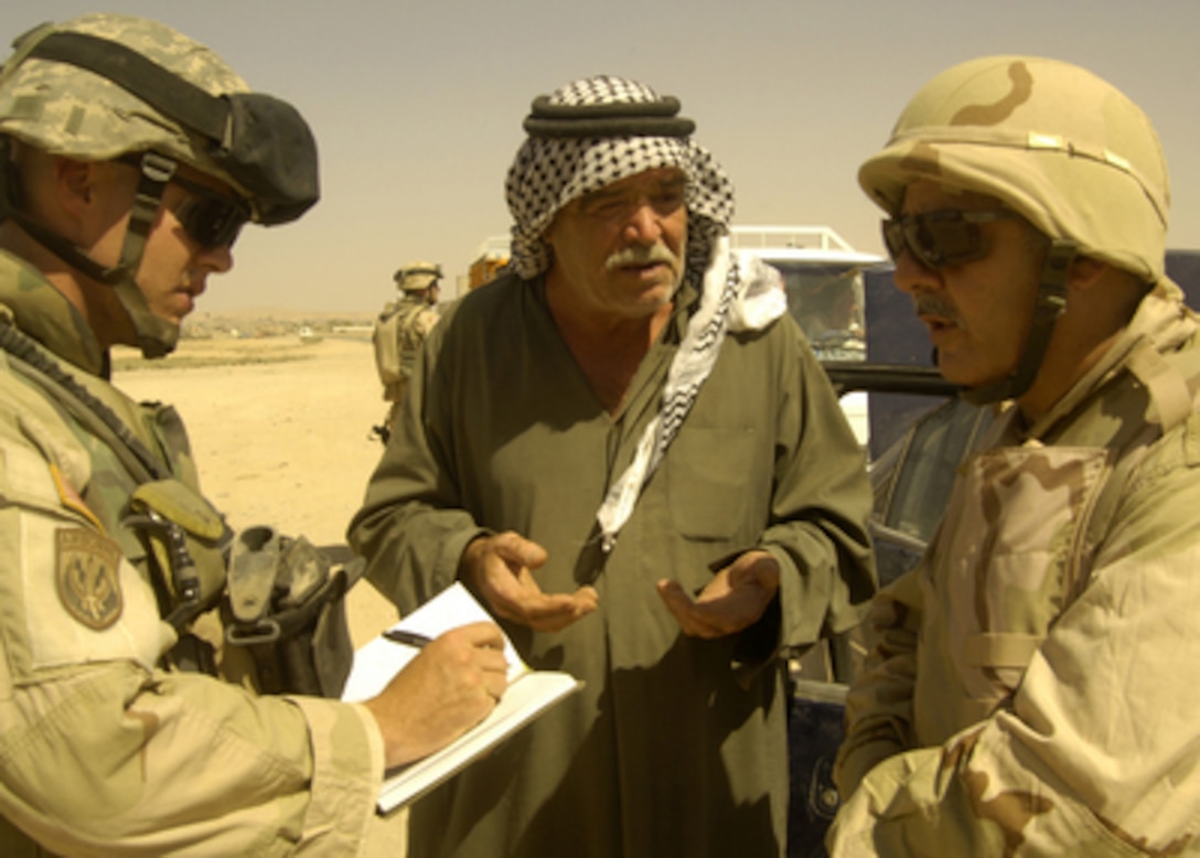 Staff Sgt. Brad Stewart (left) takes notes as he and an interpreter conduct a field interview with an Iraqi citizen at a checkpoint outside Tal Afar, Iraq, on Aug. 19, 2005. Stewart is attached to Tactical PSYOP Detachment 1720. 