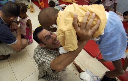 AFRICA -- Capt. Chuck Rohrig entertains a youngster while volunteering at an orphanage here.  U.S. servicemembers volunteer to help feed, change, bathe and clothe the infants twice a day.  Captain Rohrig is assigned to the 1st Combat Camera Squadron at Charleston Air Force Base, S.C.  (U.S. Air Force photo by Staff Sgt. Stacy L. Pearsall)