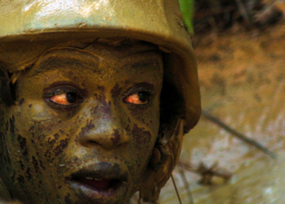 U.S. Navy Constructionman Joseph K. Otumfuor is covered with silt from a muddy trench as he runs a 3.8 mile obstacle course at the Jungle Warfare Training Center in Okinawa, Japan, on Aug. 17, 2005. Otumfuor is assigned to Naval Mobile Construction Unit 74. 