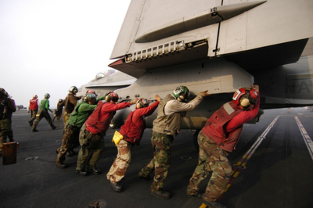 U.S. Navy flight deck personnel push an F/A-18C backwards onto an aircraft elevator on the deck of the aircraft carrier USS Kitty Hawk (CV 63) on Nov. 29, 2005. The Kitty Hawk Carrier Strike Group is operating in the western Pacific Ocean from its homeport of Yokosuka, Japan. 