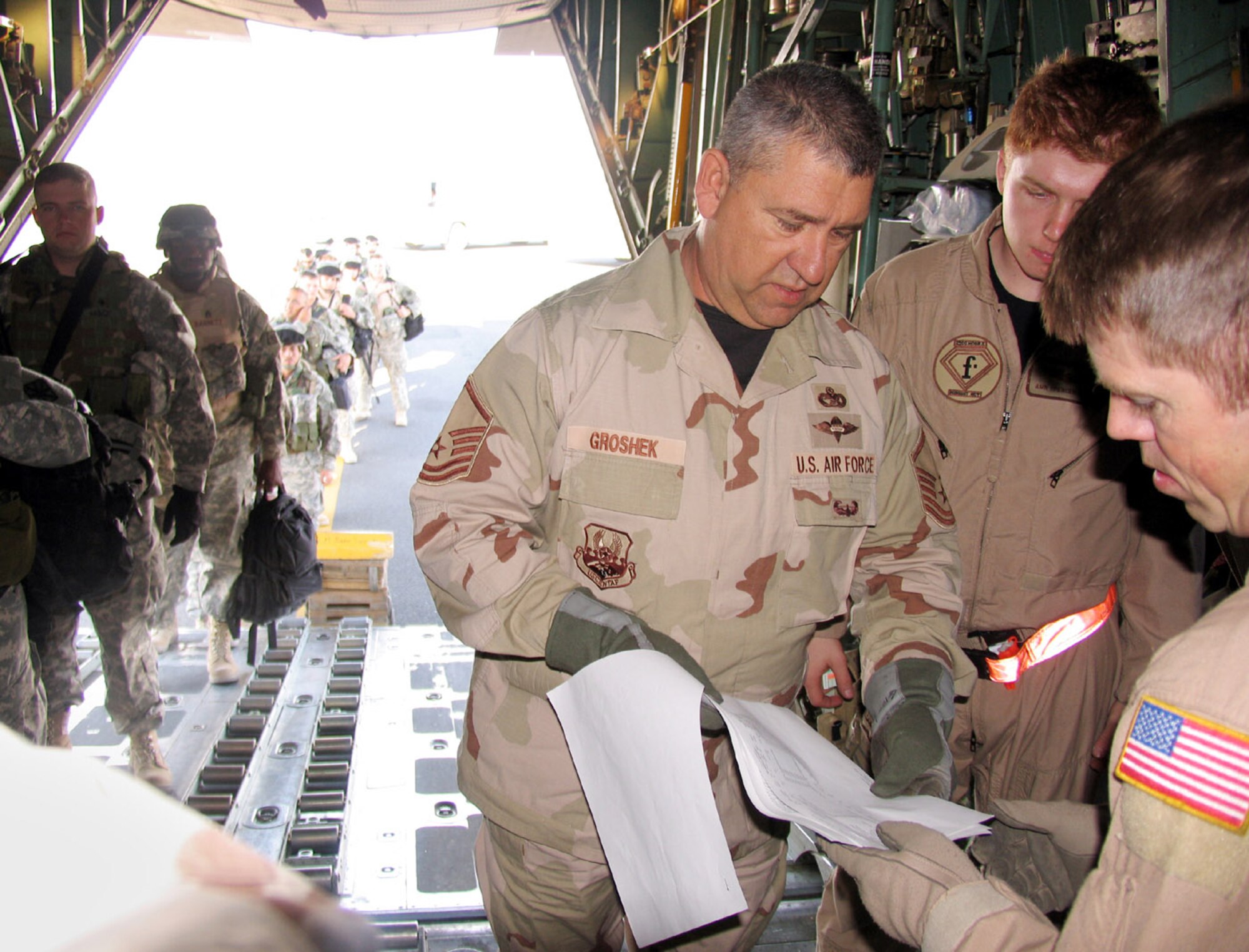 SOUTHWEST ASIA (AFPN) -- Master Sgt. Mark Groshek (center) checks a passenger manifest with Tech. Sgt. Terry Williamson (right) before departing with 44 passengers and 5,500 pounds of baggage to Iraq. Sergeant Groshek is with the 386th Expeditionary Logistics Readiness Squadron and deployed from the 34th Aerial Port Squadron at Billy Mitchell Air Reserve Station, Wis. Sergeant Williamson is with the 737th Expeditionary Airlift Squadron and deployed from the 41st Airlift Squadron at Pope Air Force Base, N.C. (U.S. Air Force photo by Staff Sgt. Scott Campbell) 