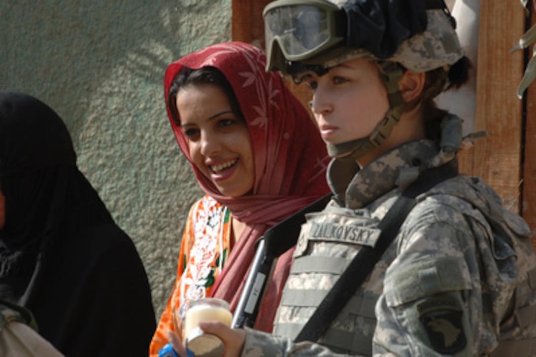 Army Pfc. Janelle Zalkovsky hands out humanitarian aid items to local citizens in Thyad, Iraq, on Dec. 4, 2005. Zalkovsky is attached to the Civil Affairs Unit of the 1st Battalion, 320th Field Artillery Regiment, 101st Airborne Division deployed from Fort Campbell, Ky. 