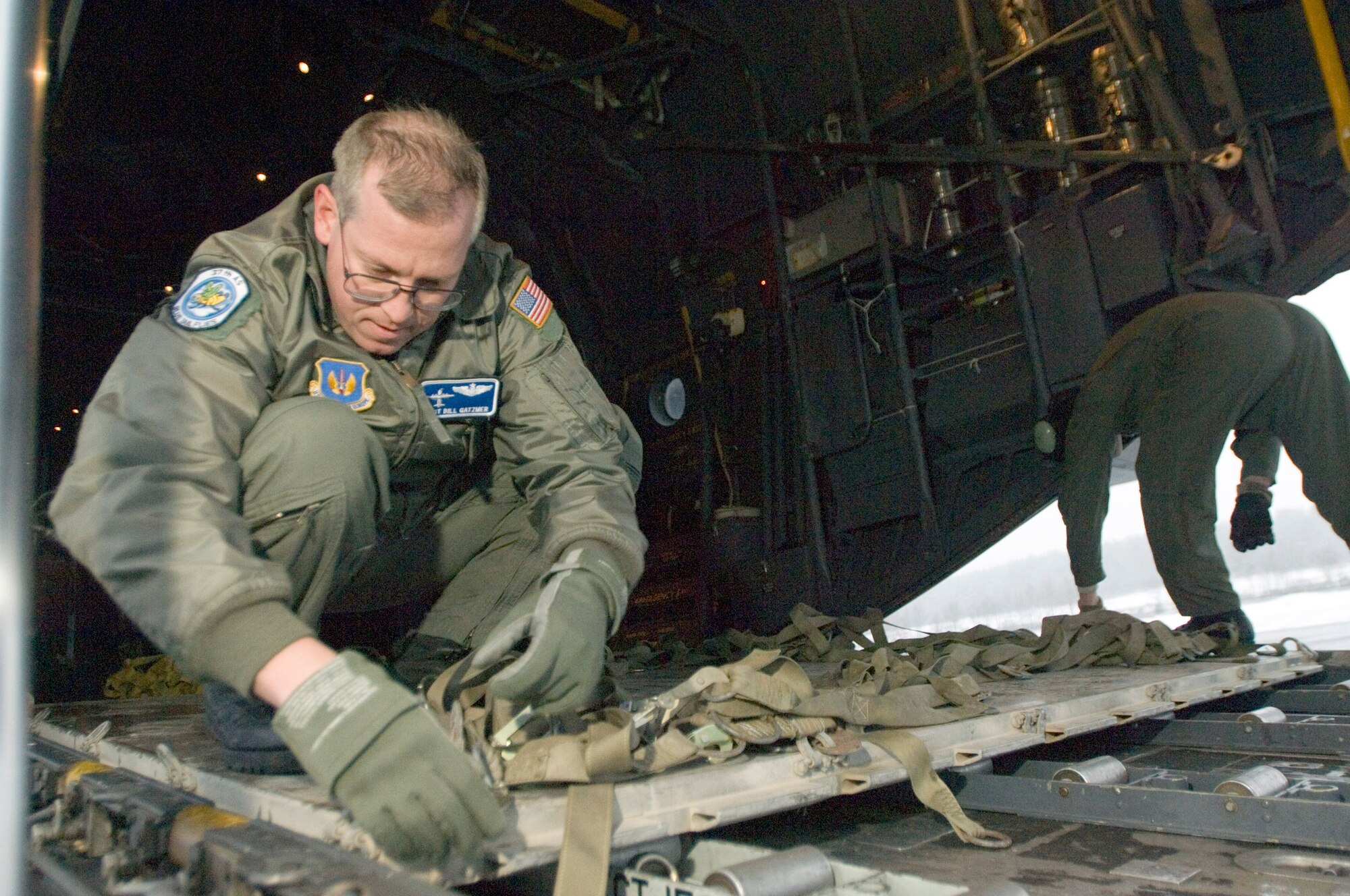 GRAFENWOEHR, Germany (AFPN) -- Master Sgt. Bill Gatzmer removes pallet straps on a C-130 Hercules. His crew flew Romanian soldiers and their gear to Grafenwoehr, Germany, for training. Sergeant Gatzmer is a loadmaster with the 37th Airlift Squadron at Ramstein Air Base, Germany. (U.S. Air Force photo by Master Sgt. John E. Lasky)