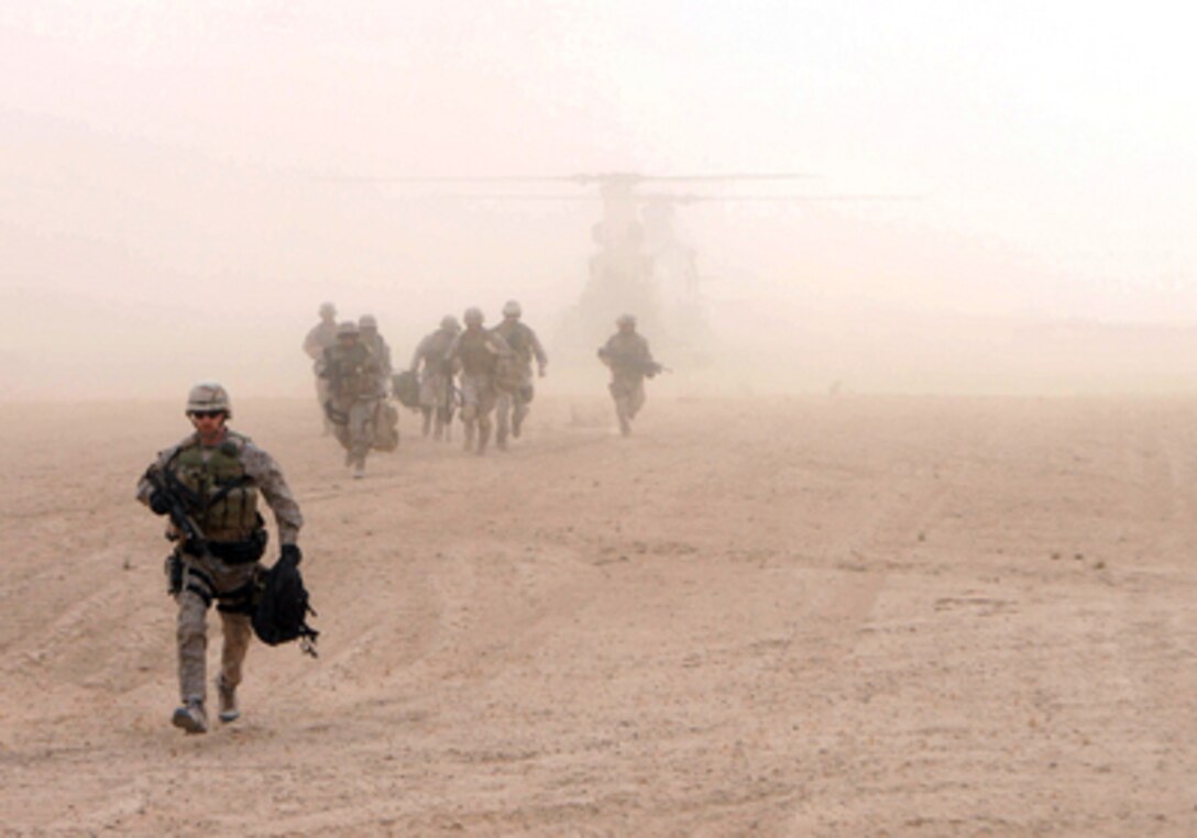 U.S. Marines emerge from a cloud of dust kicked up by the rotor wash of a CH-46 Sea Knight helicopter in Iraq on Dec. 4, 2005. The Marines and Navy Criminal Investigation Service agents are investigating the site as an alleged insurgent sniper range. 