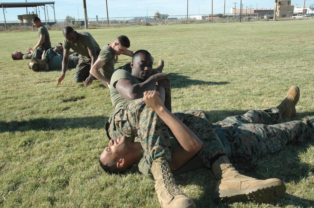 Sgt. Erik Costner (top), Marine Aviation Logistics Squadron 13 calibration technician and native of Buffalo, N.Y., performs an arm bar from the mount on Cpl. Dedrick McDannell, MALS-13 micro miniature electrician and native of Onley, Va., Dec. 7 at Ramada Field here as part of a martial arts instructor training course.