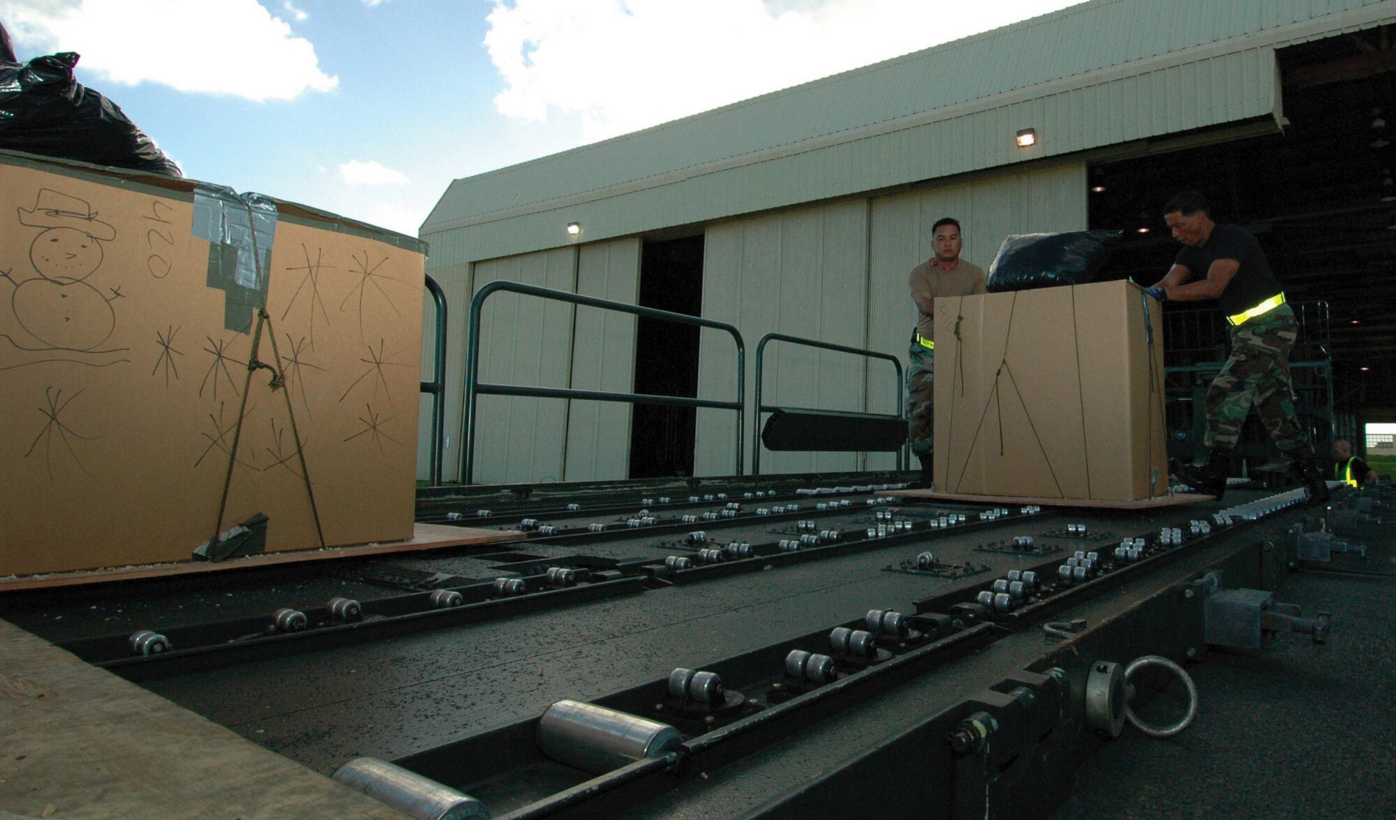 ANDERSEN AIR FORCE BASE, Guam (AFPN) -- Staff Sergeant Jesse Aquino and Senior Airman Ronald Raguindin load pallets filled with supplies for the Micronesian islanders The donated food items will be used in this year's Operation Christmas Drop, a 53-year-old tradition. C-130 Hercules aircraft from Yokota Air Base, Japan, loaded up the donated gifts and "delivered" them via parachute to the islanders. Sergeant Aquino and Airman Raguindin are air transportation journeymen with the 44th Aerial Port Squadron here. (U.S. Air Force photo by Staff Sgt. Karen J. Tomasik)