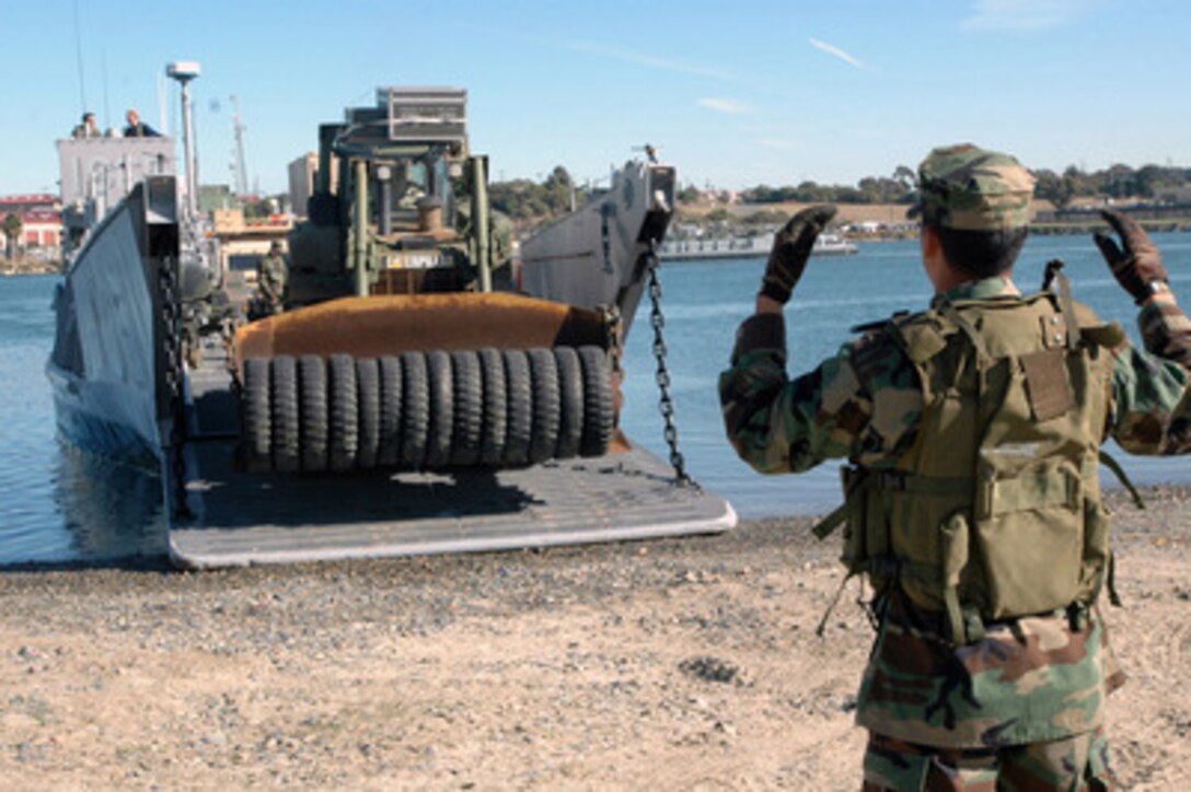 Petty Officer 3rd Class Guadelupe Rivera directs the driver of a U.S. Marine bulldozer off of a landing craft at the Del Mar Boat Basin at Camp Pendleton, Calif., on Dec. 5, 2005. The landing craft is transporting Marines of the 11th Marine Expeditionary Unit and their equipment from the amphibious assault ship USS Peleliu (LHA 5) to Camp Pendleton. Peleliu is underway off the coast of Southern California for naval exercises in preparation for its upcoming deployment. 
