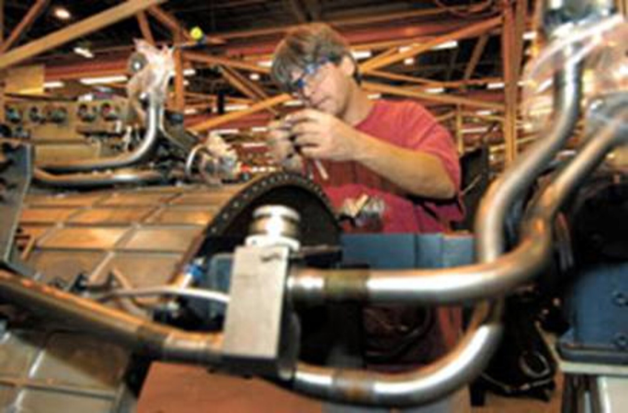 Mark Jansing attaches safety cabling to bolts on an F110 augmenter control during depot maintenance recently. (Air Force photo by Margo Wright) 