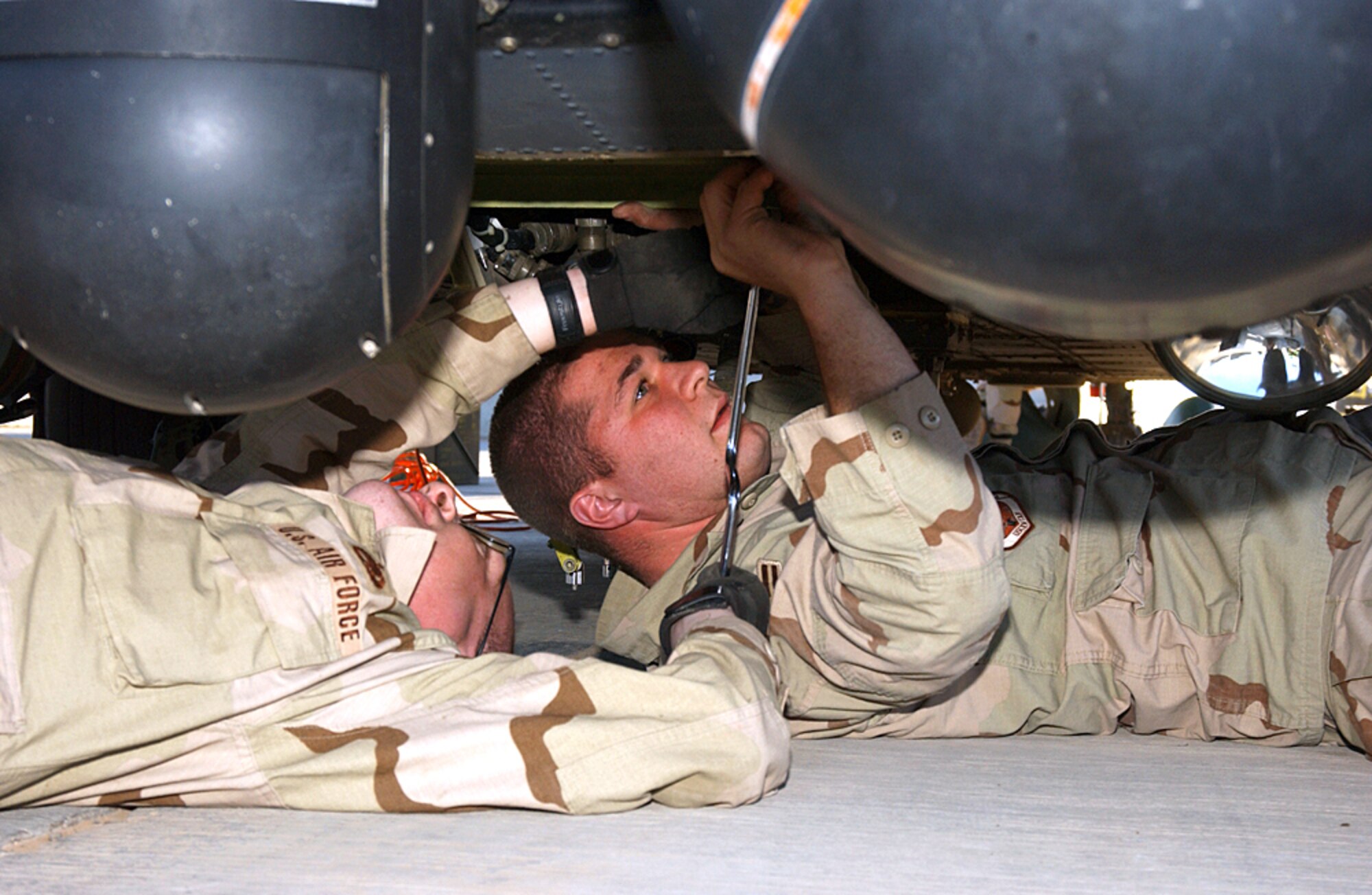 BALAD AIR BASE, Iraq (AFPN) -- Airman 1st Class Nicholas Bulduc (left) and Staff Sgt. Jonathan Beach replace the systems electronics unit that controls the HH-60G Pave Hawk helicopter's infrared sensors. Airman Bulduc and Sergeant Beach are with the 64th Expeditionary Helicopter Maintenance Unit. (U.S. Air Force photo by Tech. Sgt. Pamela Anderson)        