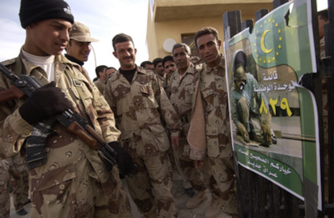 Iraqi soldiers read a poster outside a polling station as they wait in line to vote along with other Iraqi security forces in Hayji, Iraq, on Dec. 12, 2005. Iraqi citizens will be voting on Dec. 15, 2005, to elect Iraq's first free, permanent parliamentary government. 