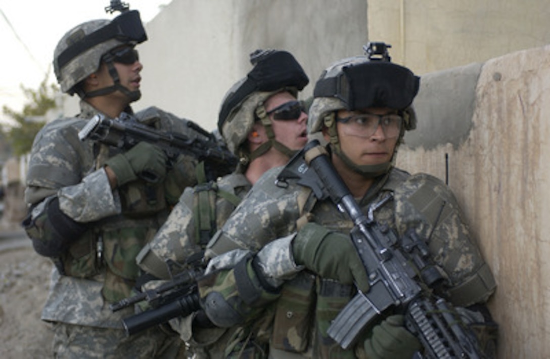 U.S. Army Sgt. Jose Rivera (right), Pfc. Richard Robinson (center) and Spc. Diego Cruz wait for the signal to enter a house while conducting a foot patrol in Bayji, Iraq, on Dec. 10, 2005. The soldiers are attached to 1st Battalion, 187th Infantry Regiment, 3rd Brigade Combat Team, 101st Airborne Division, deployed from Fort Campbell, Ky. 