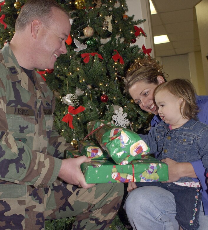 KEESLER AIR FORCE BASE, Miss. -- Chaplain (Capt.) Ken Fisher, left, gives Master Sgt. Nicole Pearson and her 1-year-old daughter, Olivia, a present. Captain Fisher is with the 47th Flying Training Wing. Sergeant Pearson is with the 81st Surgical Operations Squadron. (U.S. Air Force photo by Kemberly Groue)