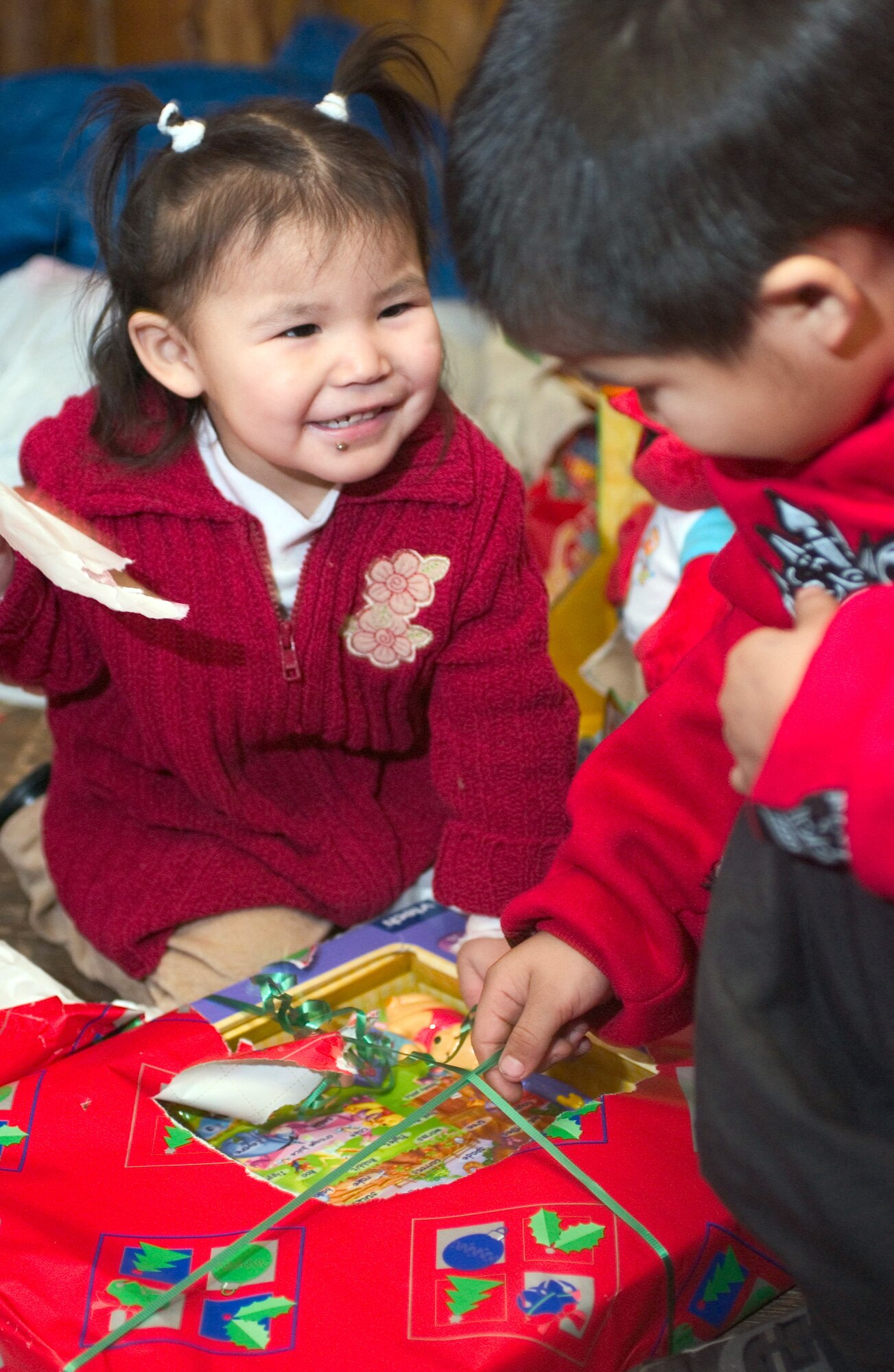 ARCTIC VILLAGE, Alaska (AFPN) -- Kyla Nikolai (left) and her brother, Kobi unwrap a present from Santa. Santa traveled with the 517th Airlift Squadron to Artic Village, Alaska, Dec. 13. The children and community gathered in the village town hall Dec. 13 to share their culture with the visiting Airman and their families. The 517th Airlift Squadron came to the village's aid in 1967 and has made an annual visit ever since. (U.S. Air Force photo by Airman 1st Class Garrett Hothan)