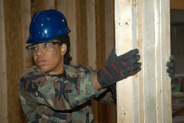 Senior Airman Soyica Hinkle, an electrical systems apprentice, holds a newly erected wall in place until it is secured.  Airman Hinkle is a member of the 434th Civil Engineering Squadron, Air Force Reserve Command, Grissom Air Reserve Base, Ind
