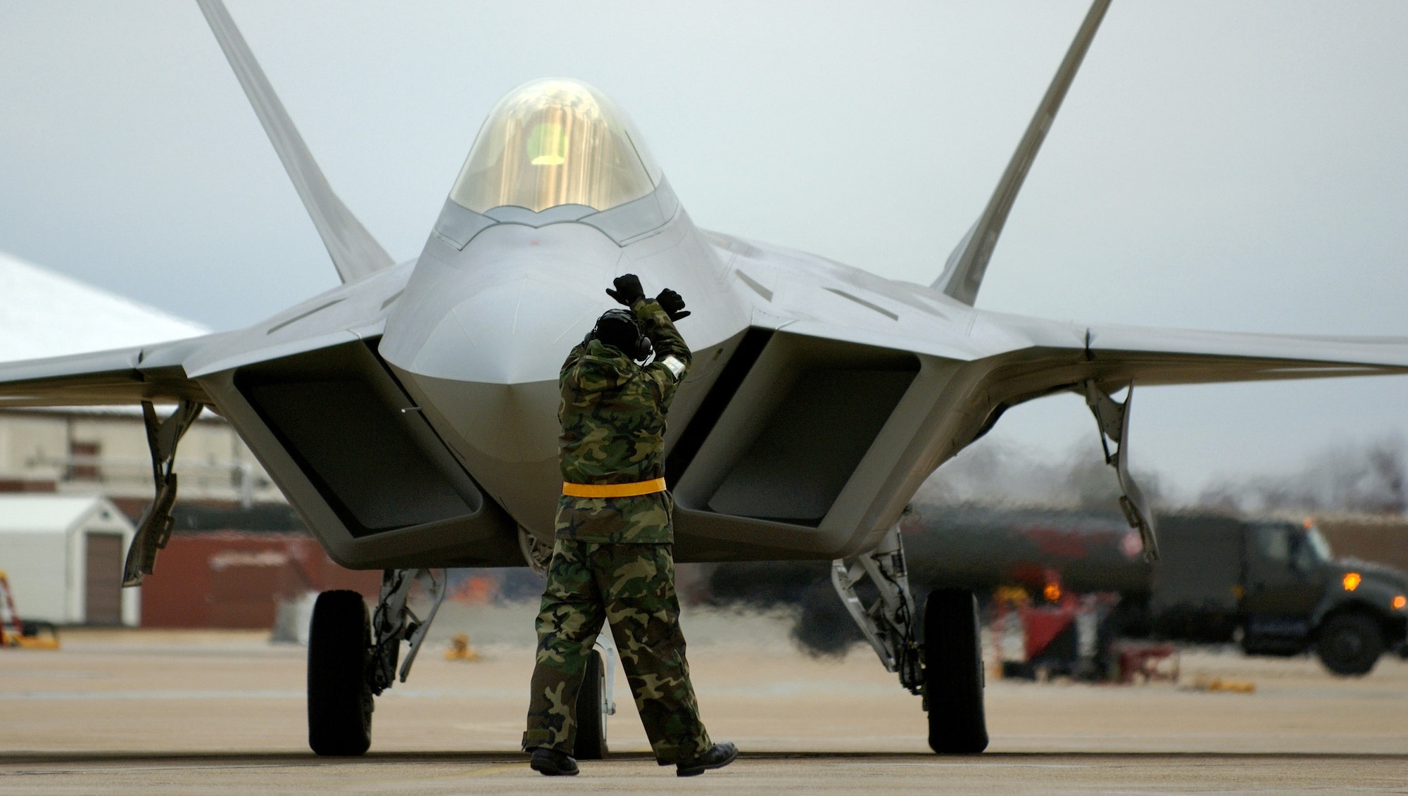 LANGLEY AIR FORCE BASE, Va. (AFPN) -- Crew chief Staff Sgt. Adam Murtishaw guides an F-22A Raptor into its parking space after a Dec. 14 mission. The 27th Fighter Squadron earned initial operating capability today, which means the stealth jet is combat ready. Sergeant Murtishaw is with the 27th Aircraft Maintenance Unit. (U.S. Air Force photo by Tech. Sgt. Ben Bloker)