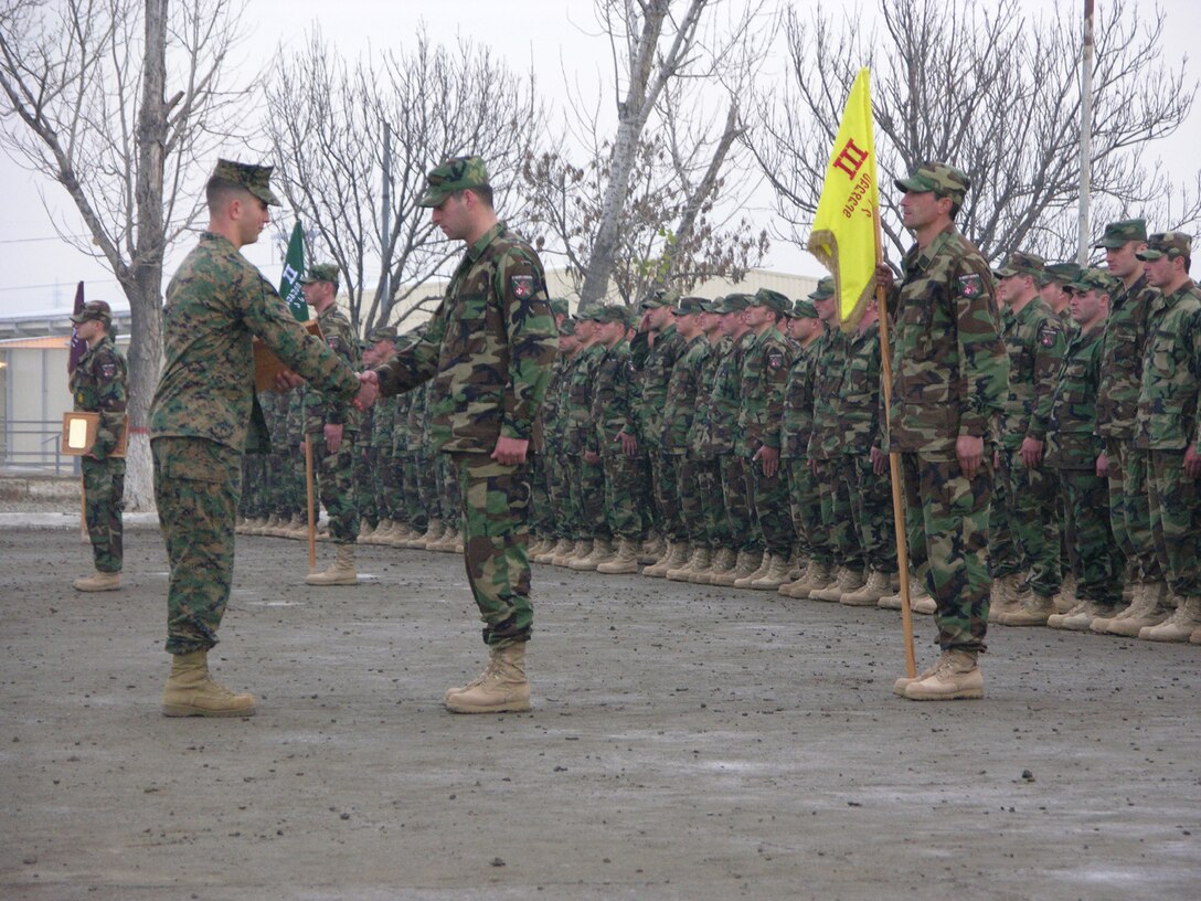 Capt. Gregory Starace, 28, a Georgia Sustainment and Stability Operations Program trainer for the Georgian 22nd Light Infantry Battalion?s Charlie Company and native of Paramus, N.J., presents the Charlie Co. commnander with a plaque during the GSSOP graduation ceremonyat Krtsanisi, Georgia Dec. 16, 2005. Training the 22nd Battalion under the GSSOP is further evidence that the U.S. and Georgia are continually building a solid alliance as partners in the Global War on Terror. A primary effect of the GSSOP is that the new and improved Georgian Army in conjunction with U.S. trained Georgian law enforcement are more capable of securing the Georgian boarders, keeping the Caucus Region off the ever shrinking list of potential safe havens for terrorists.