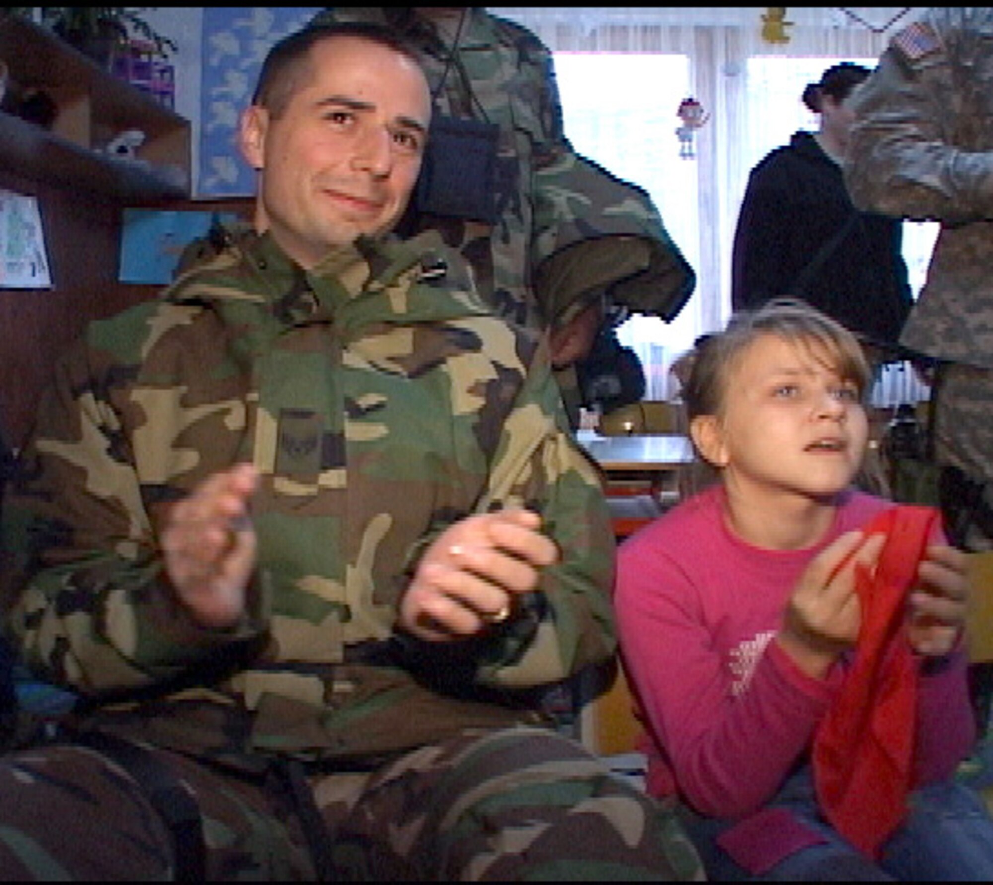 PRISTINA, Serbia and Montenegro (AFPN) -- Staff Sgt. James Normandin enjoys a production by the children of the community center here. U.S. servicemembers deployed with the Kosovo Force at NATO Base Film City, Kosovo, raised more than $1,200 to buy fuel to keep the center's generator running. The generator provides heat and electricity to the center throughout the winter. (U.S. Air Force photo)