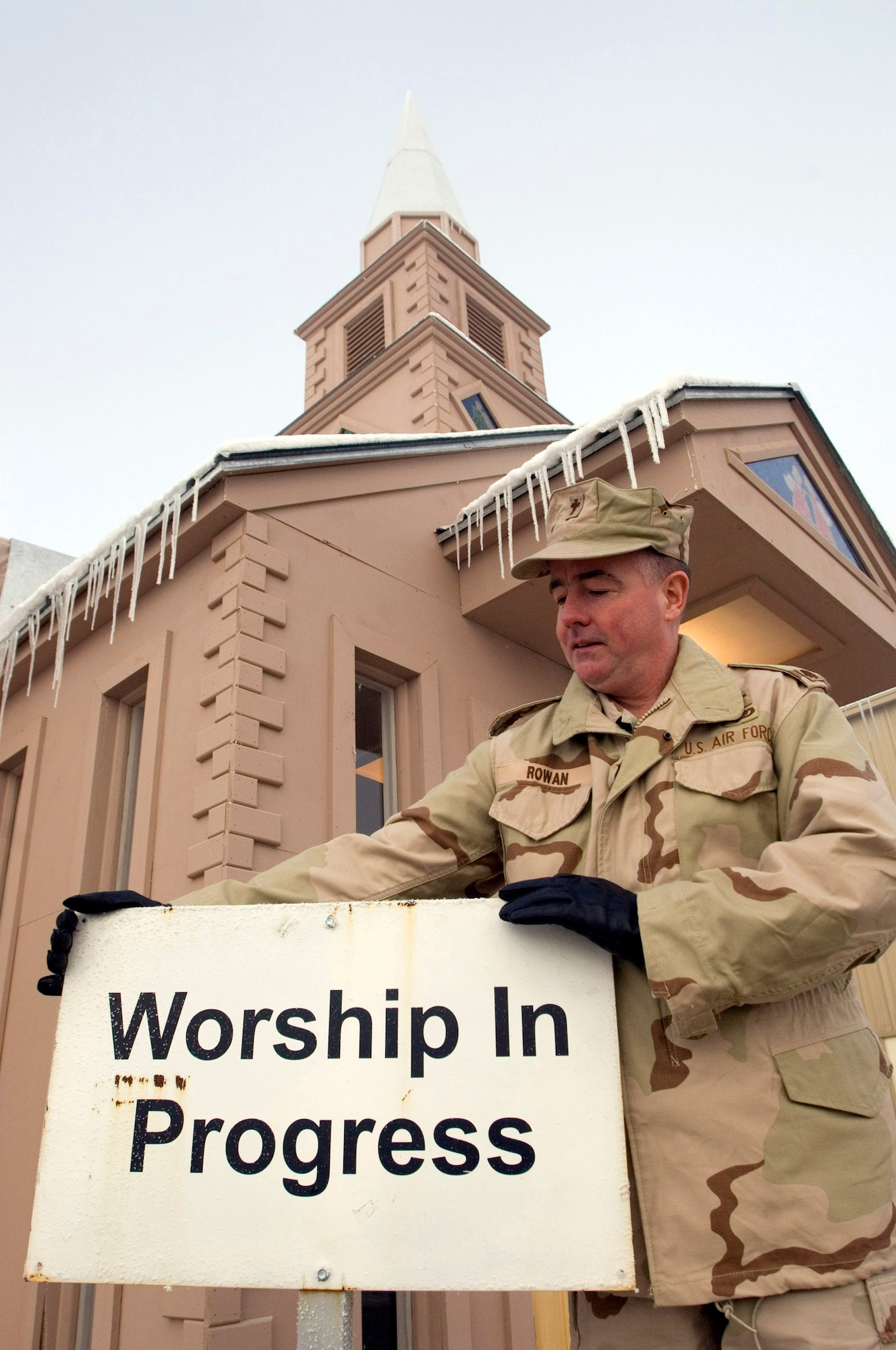 MANAS AIR BASE, Kyrgyzstan (AFPN) -- Chaplain (Maj.) Mark Rowan places the "Worship in Progress" sign outside the chapel here. Volunteers have renovated the chapel and built a steeple. It is the tallest in the region. Major Rowan is the Catholic chaplain for the 376th Air Expeditionary Wing. (U.S. Air Force photo by Master Sgt. John E. Lasky)