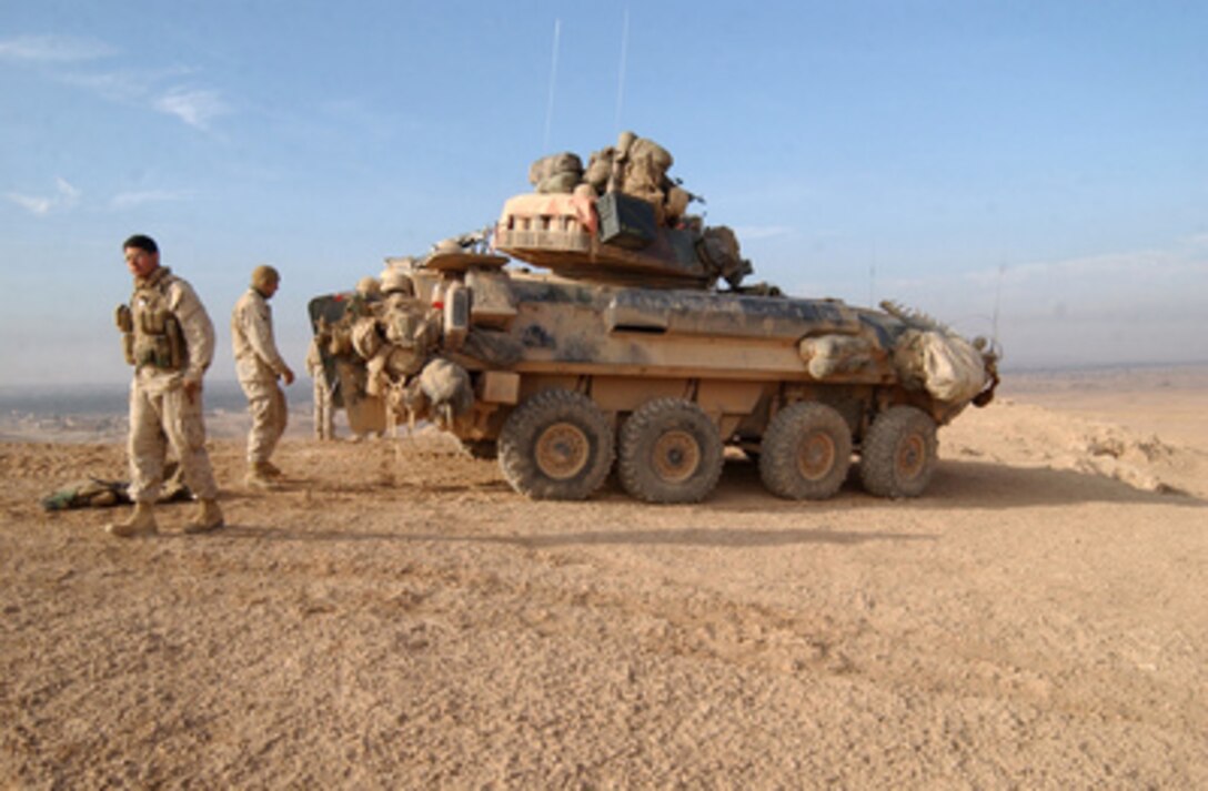 U.S. Marine Cpls. Joshua Sanchez (left) and Jared Broderick take a break outside of their light armored vehicle parked on a hill overlooking the city of Hit, Iraq, on Dec. 5, 2005. Sanchez and Broderick are scouts with 2nd Platoon, Bravo Company, 1st Light Armored Reconnaissance, 13th Marine Expeditionary Unit (Special Operations Capable). 